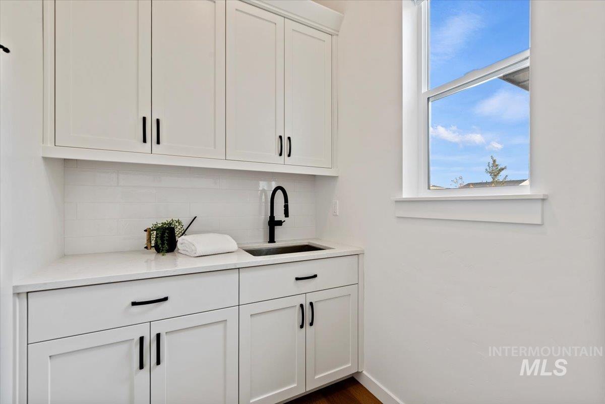 Bar featuring white cabinetry, decorative backsplash, light stone countertops, and dark wood-style floors