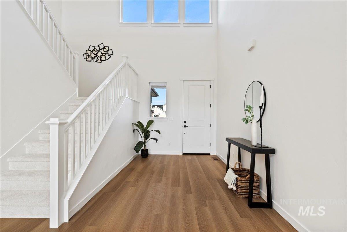 Foyer with wood finished floors, stairs, and a towering ceiling