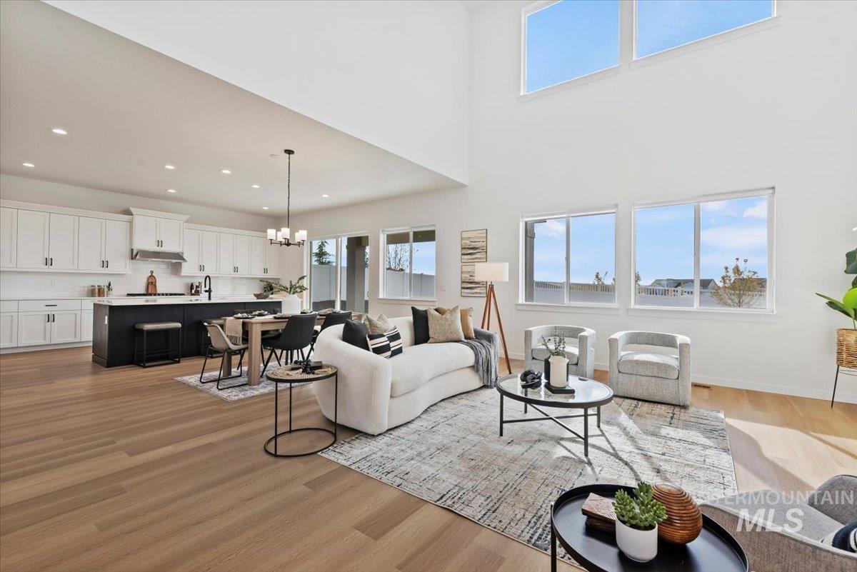 Living room featuring a chandelier, a towering ceiling, light wood finished floors, and recessed lighting
