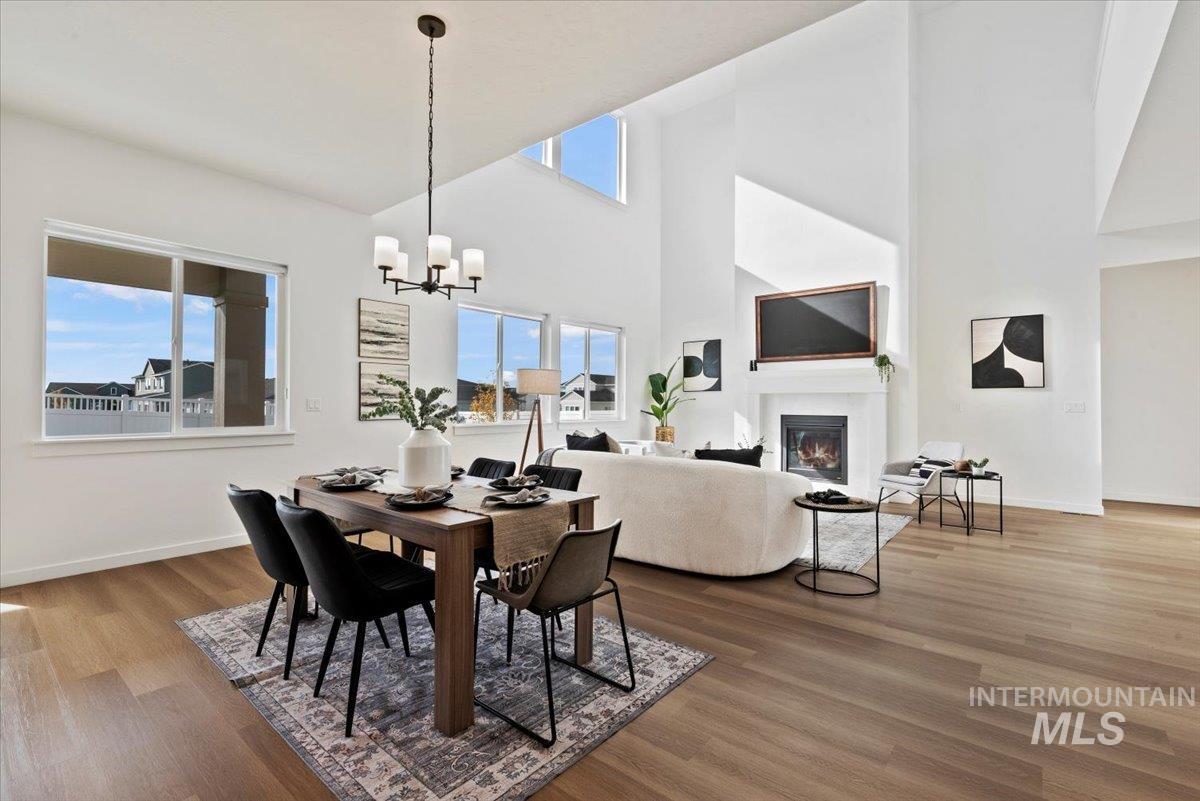 Dining room with a glass covered fireplace, high vaulted ceiling, light wood-style flooring, and a chandelier
