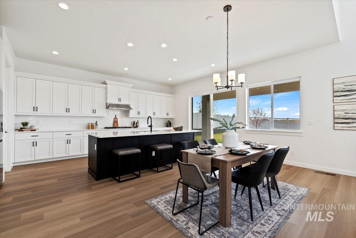 Dining space with dark wood-style floors, a chandelier, and recessed lighting