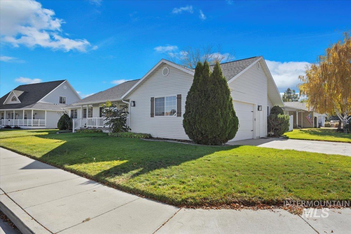 View of front of house with a front yard, concrete driveway, a garage, and a porch