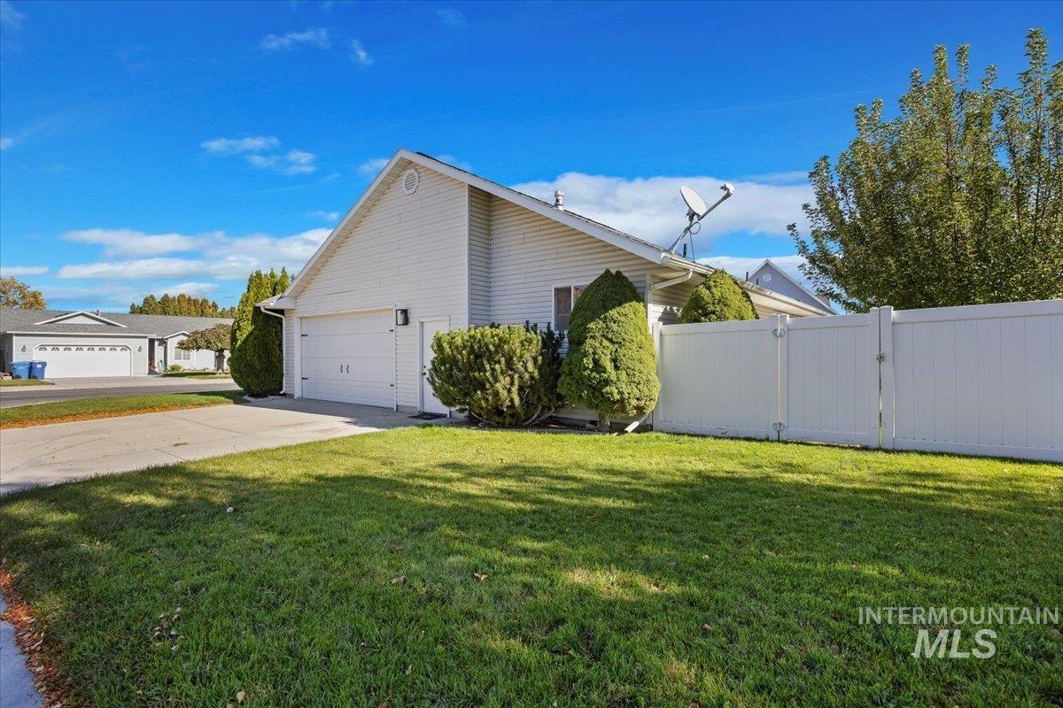 View of property exterior with concrete driveway, a garage, and a gate