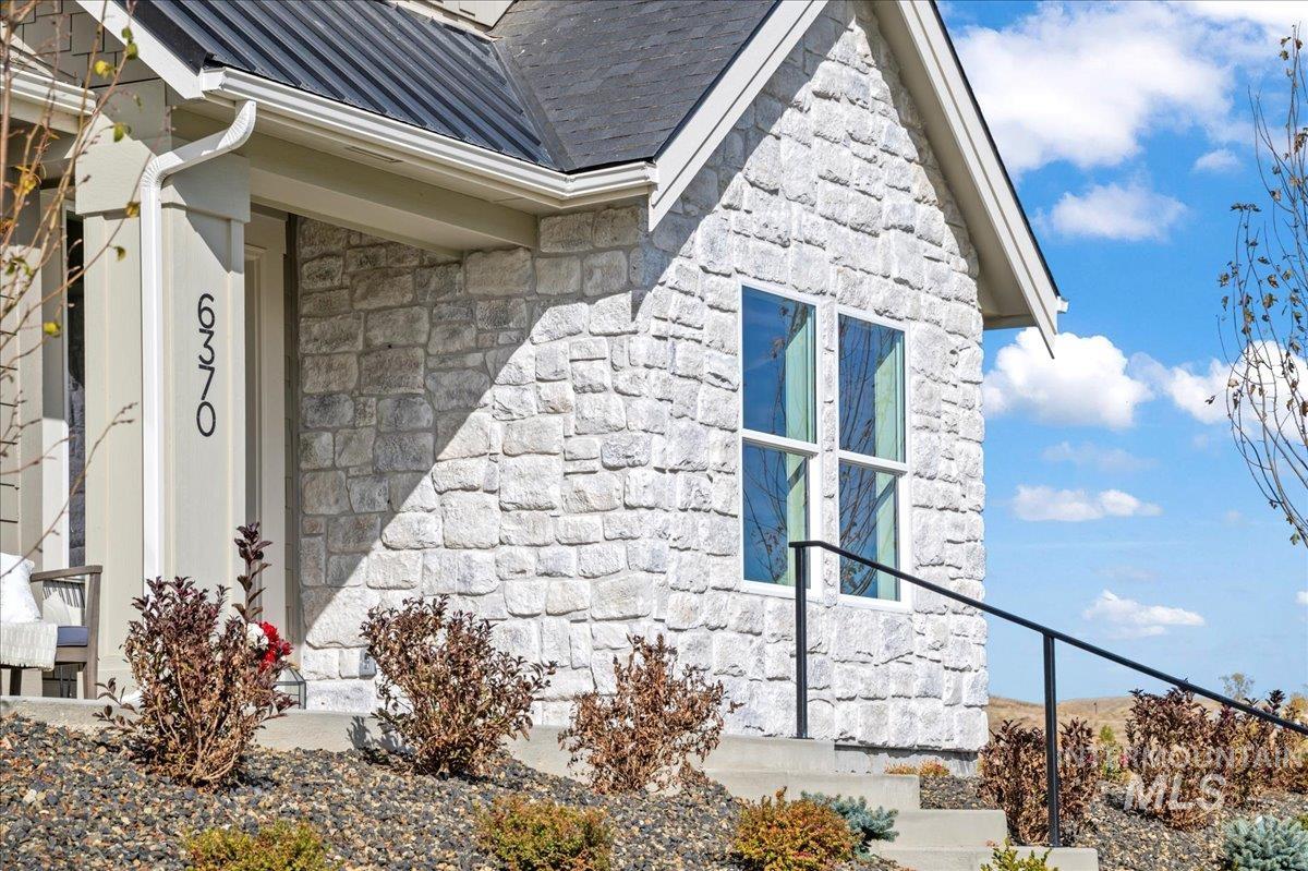 View of side of property featuring stone siding, a metal roof, and a standing seam roof