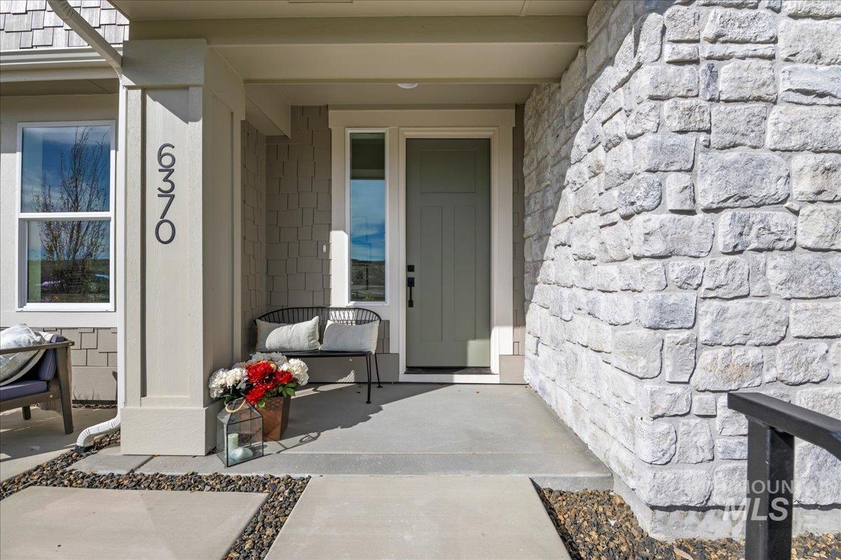 Entrance to property with covered porch and stone siding