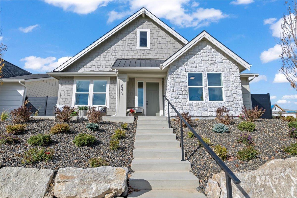 View of front facade with a standing seam roof, a metal roof, a porch, and stone siding