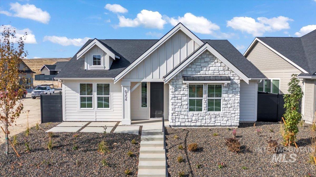 View of front facade featuring stone siding, board and batten siding, and roof with shingles