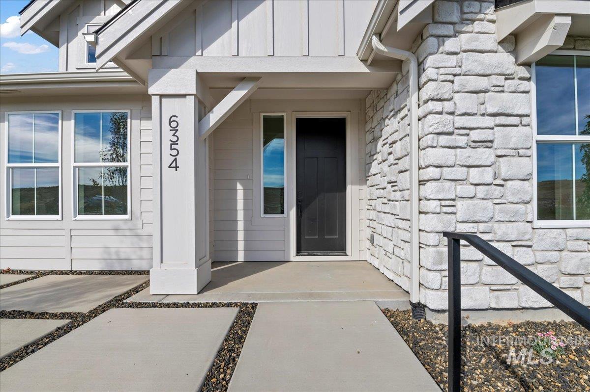 Property entrance featuring stone siding and board and batten siding