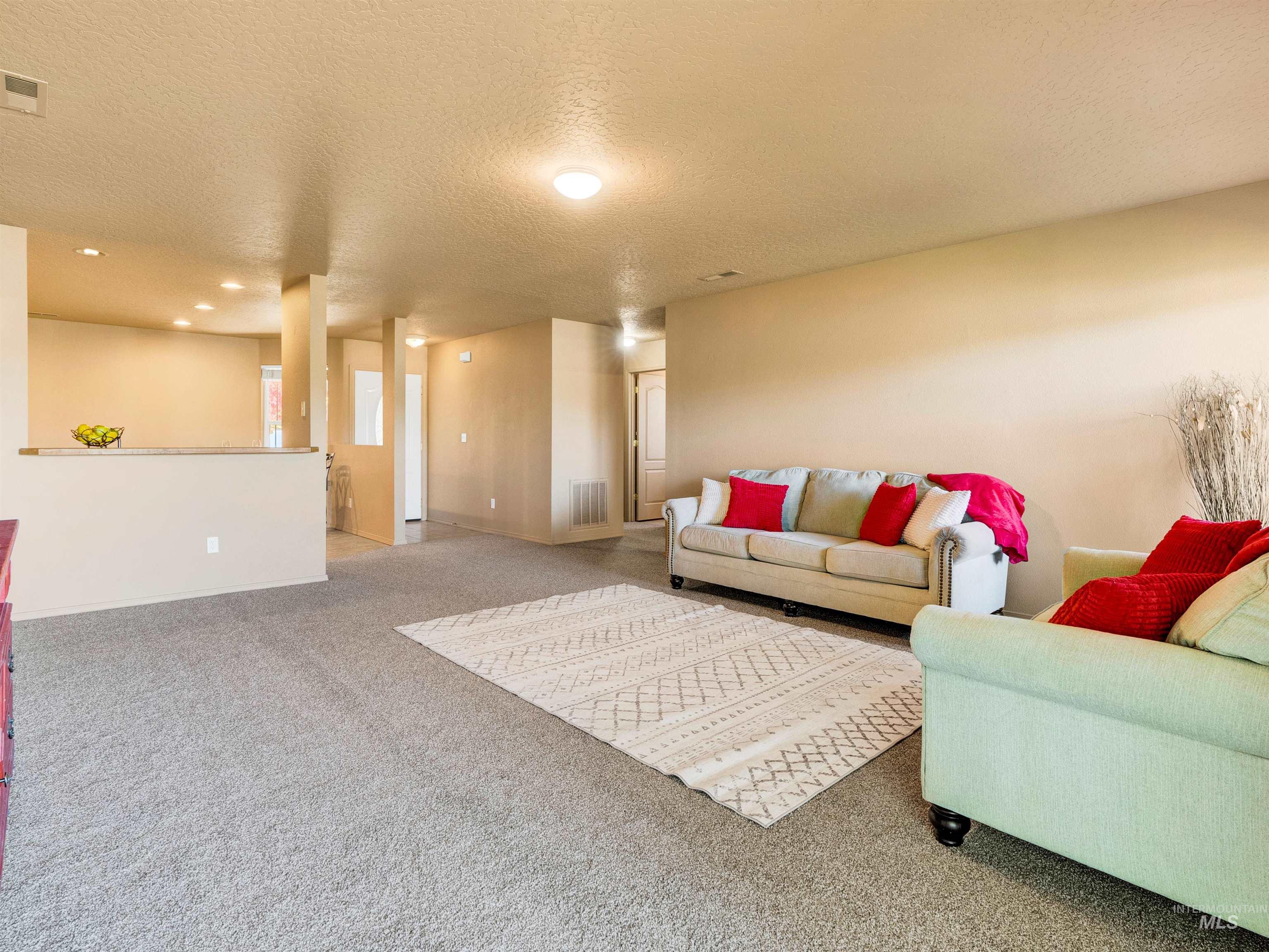 Living area featuring carpet floors, a textured ceiling, and recessed lighting