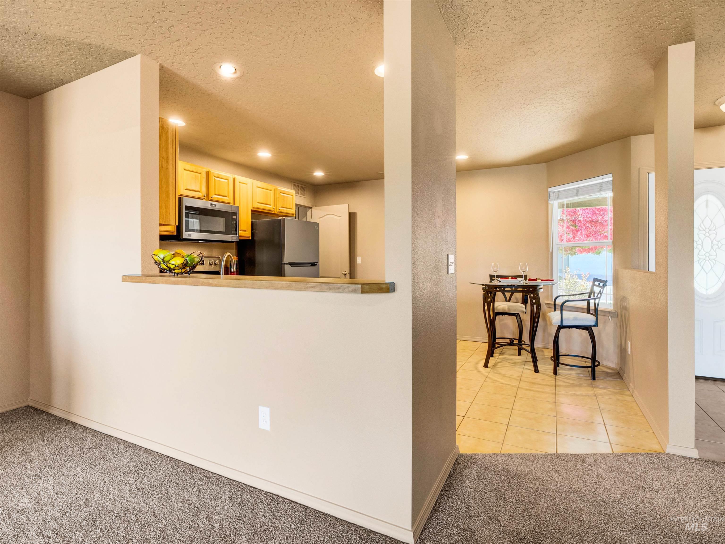 Kitchen featuring a textured ceiling, light carpet, light tile patterned floors, appliances with stainless steel finishes, and recessed lighting