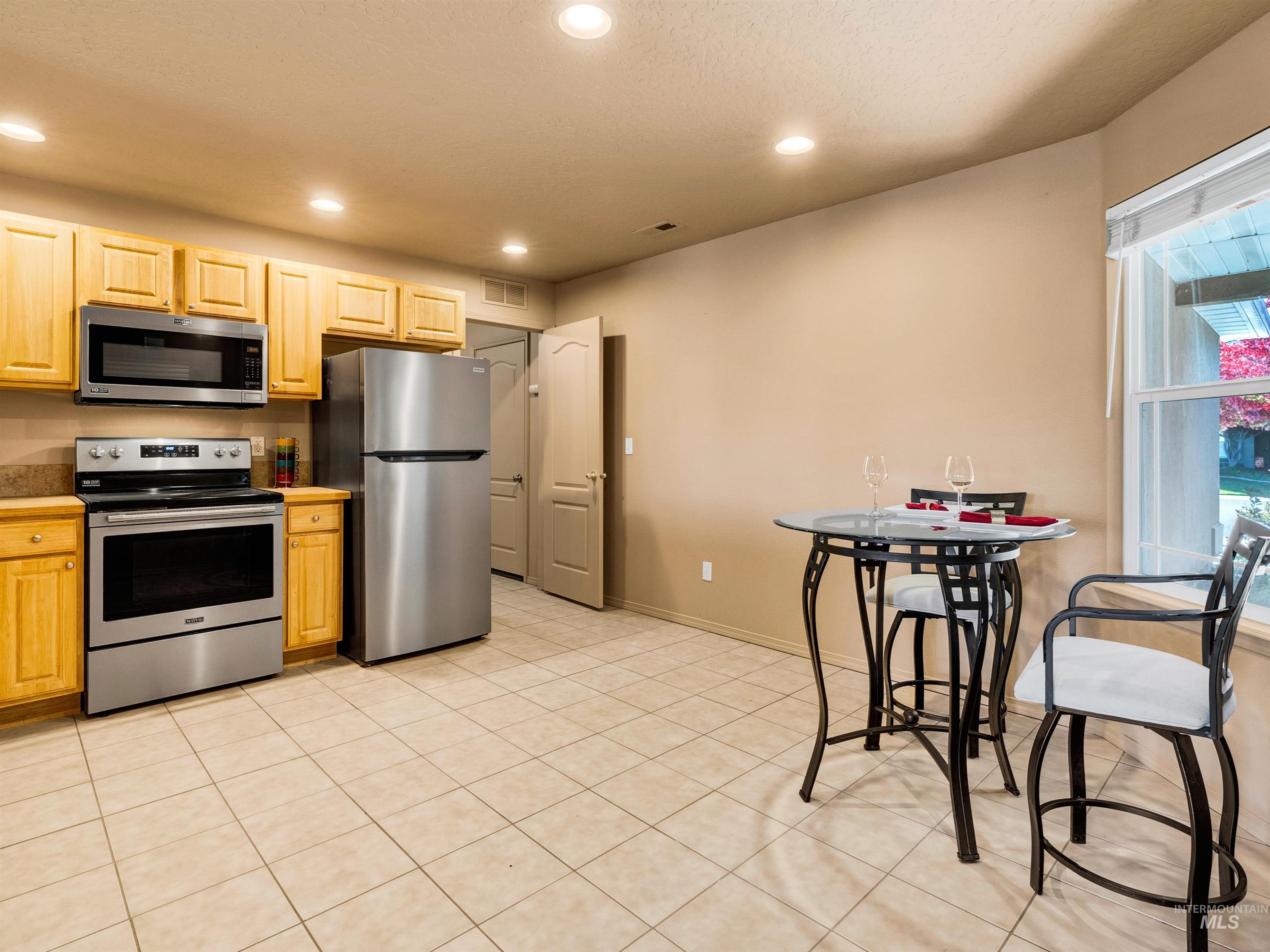 Kitchen with appliances with stainless steel finishes, recessed lighting, light tile patterned flooring, and light brown cabinetry
