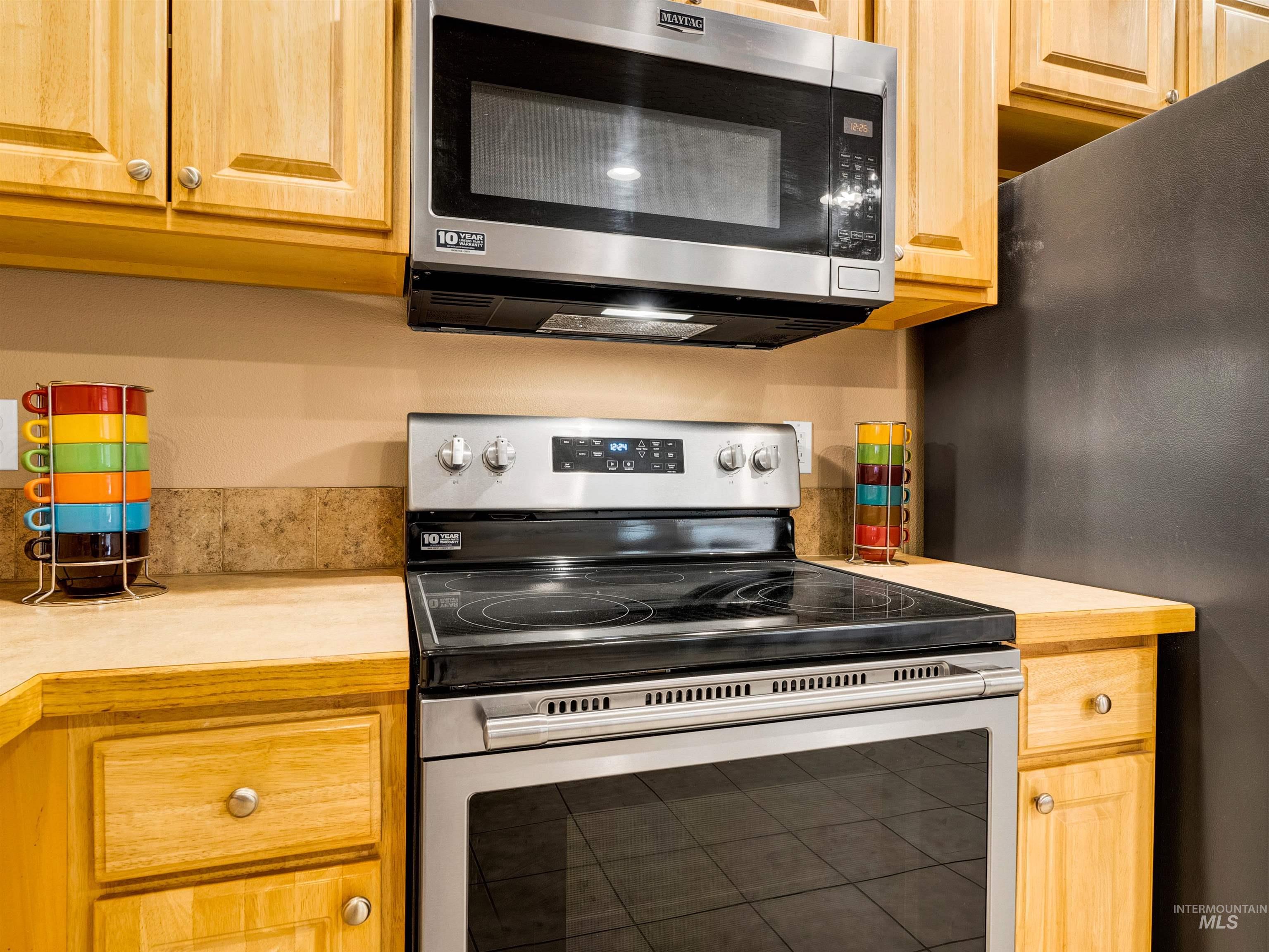 Kitchen with stainless steel appliances, light countertops, and light brown cabinetry