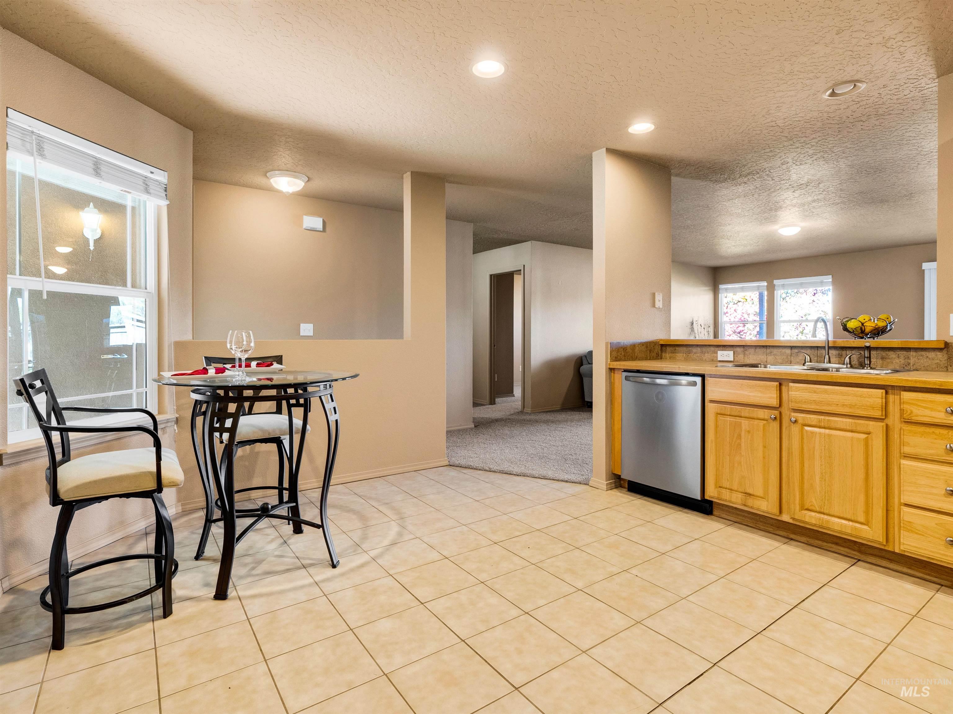 Kitchen with a textured ceiling, recessed lighting, dishwasher, light tile patterned floors, and light countertops