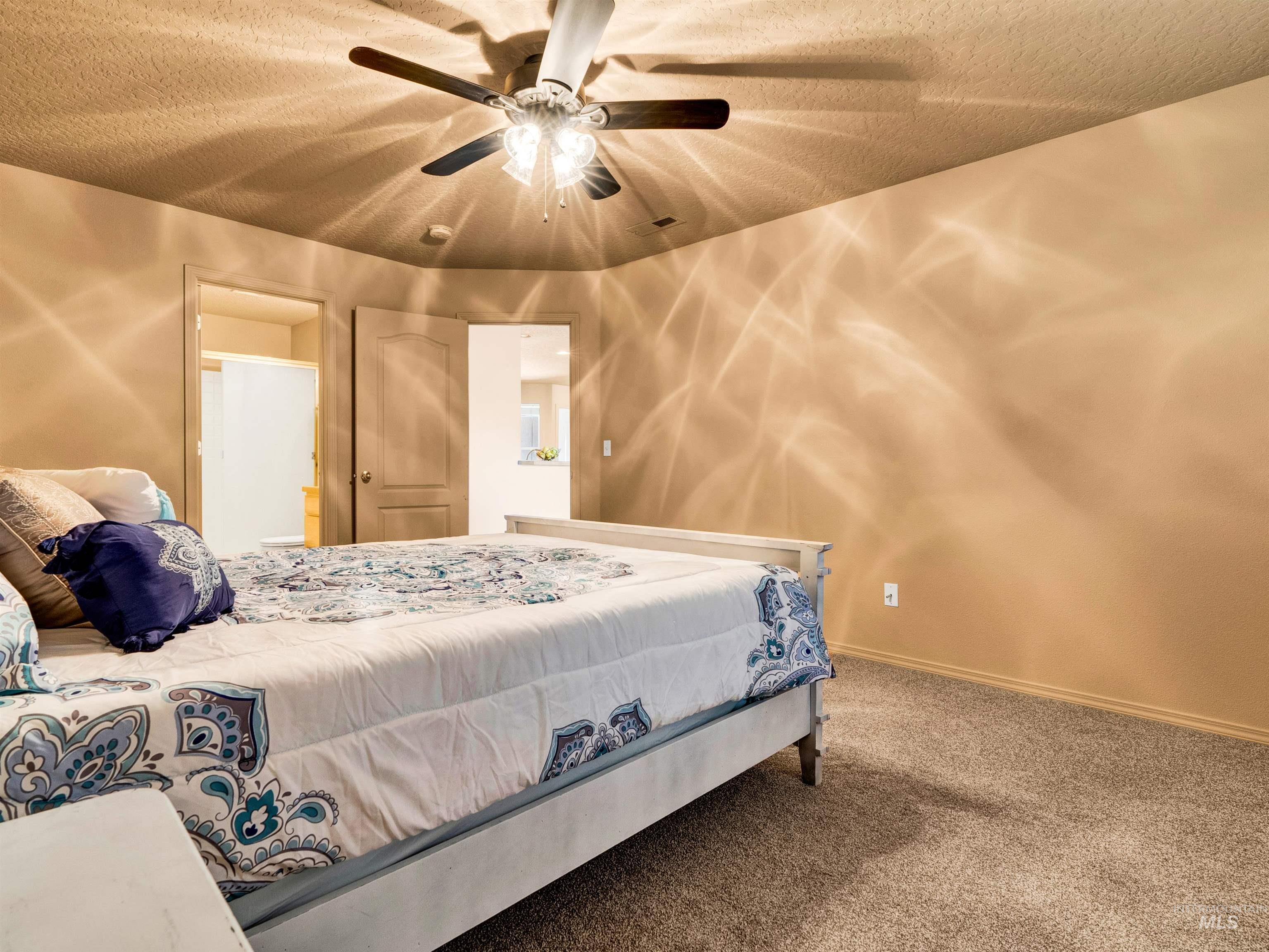 Carpeted bedroom featuring a textured ceiling and a ceiling fan