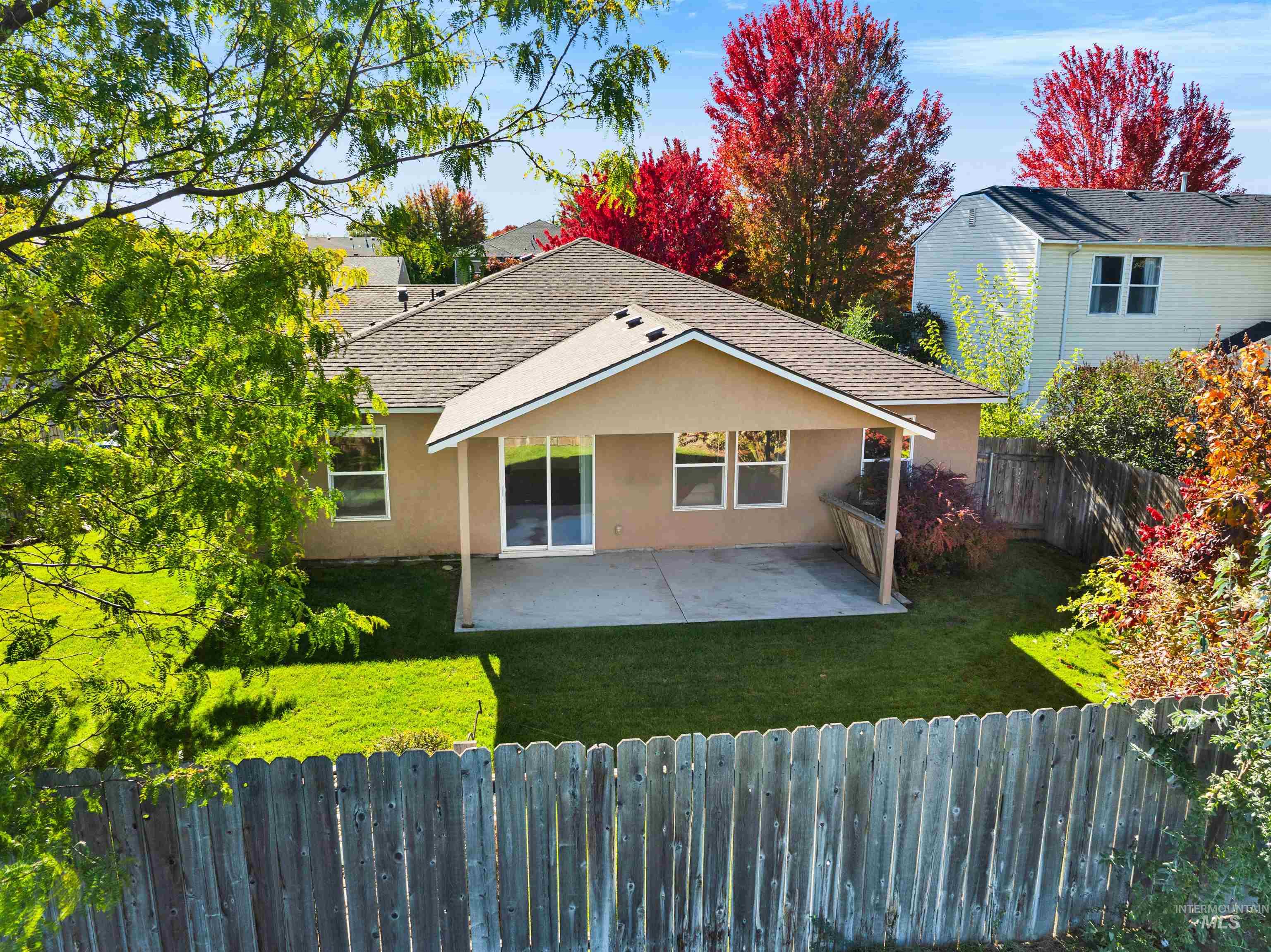 Rear view of house featuring stucco siding, a fenced backyard, a patio, and roof with shingles