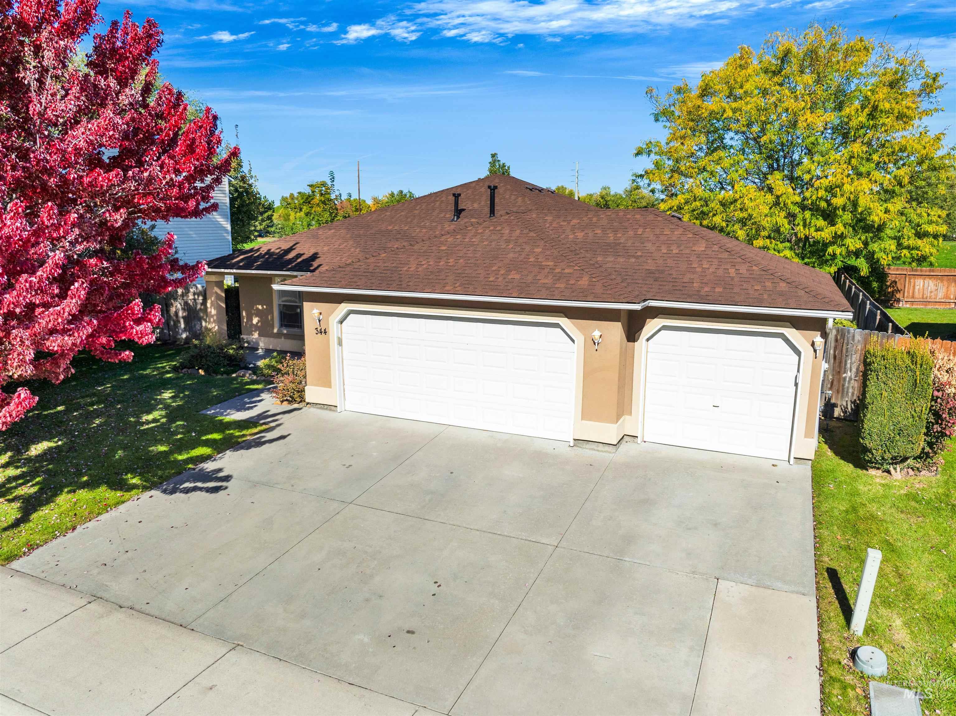 Ranch-style home with roof with shingles, a garage, stucco siding, and concrete driveway