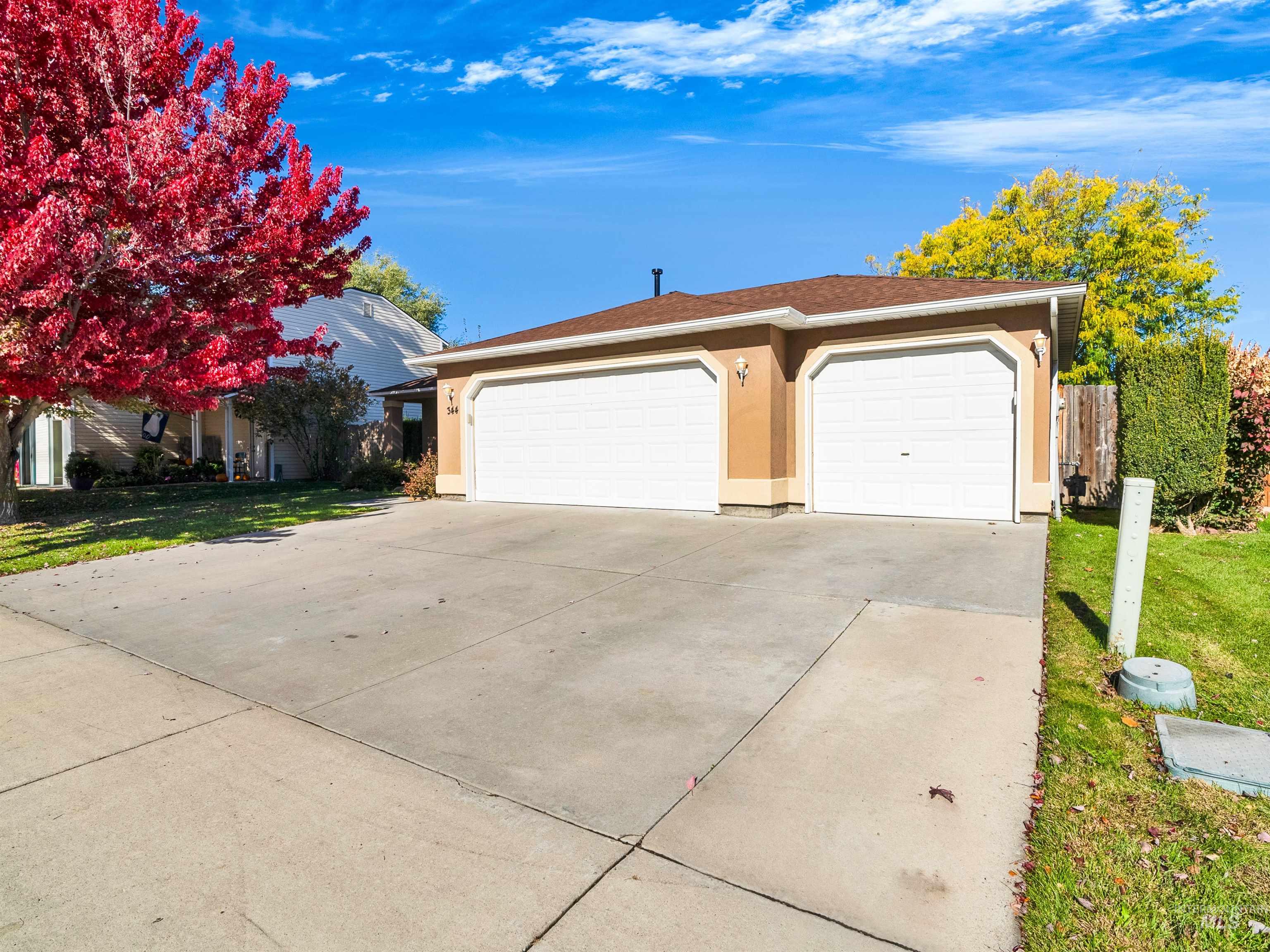Ranch-style house featuring a garage, stucco siding, and concrete driveway
