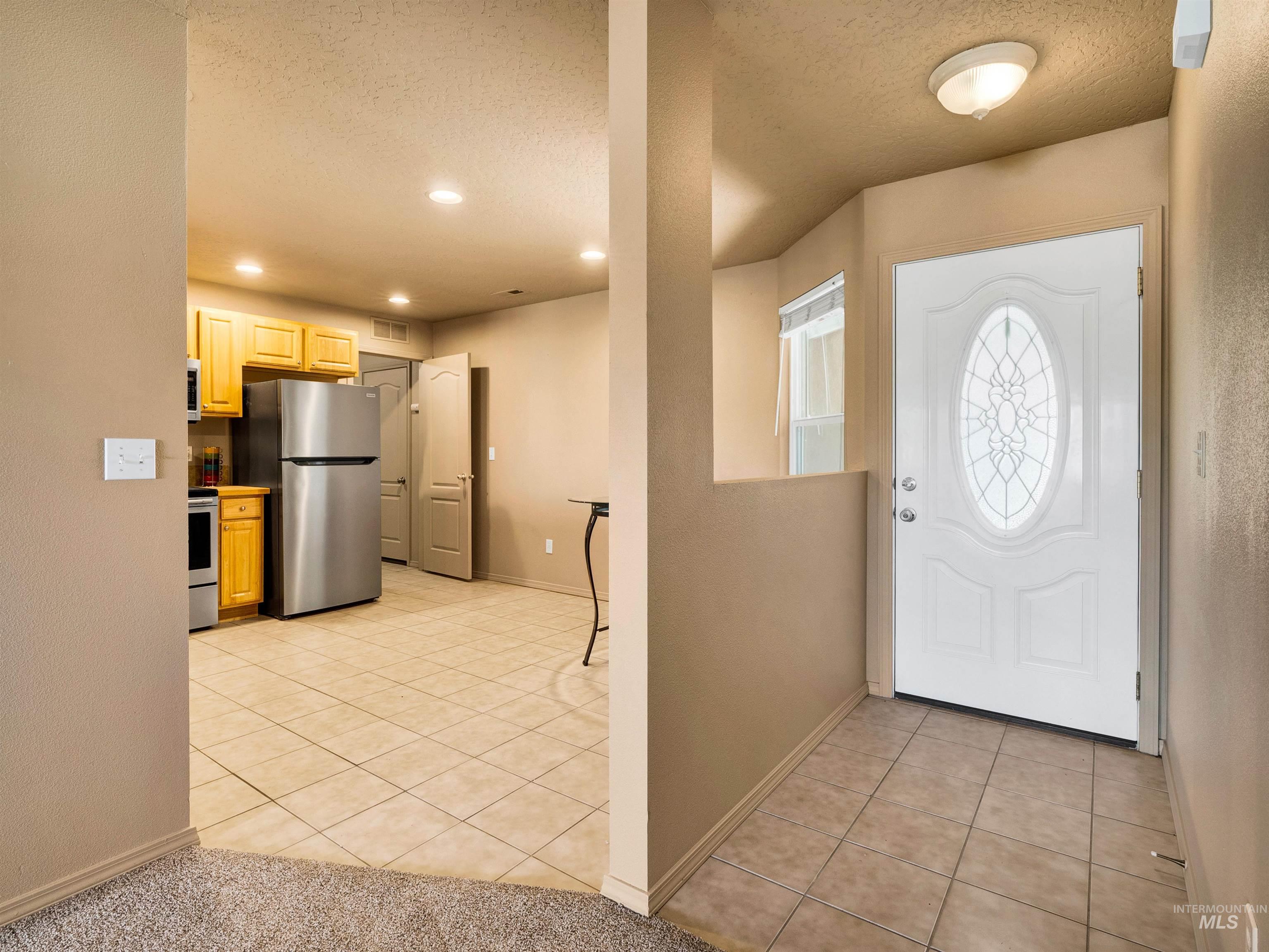 Foyer with light tile patterned flooring, a textured ceiling, a textured wall, and recessed lighting