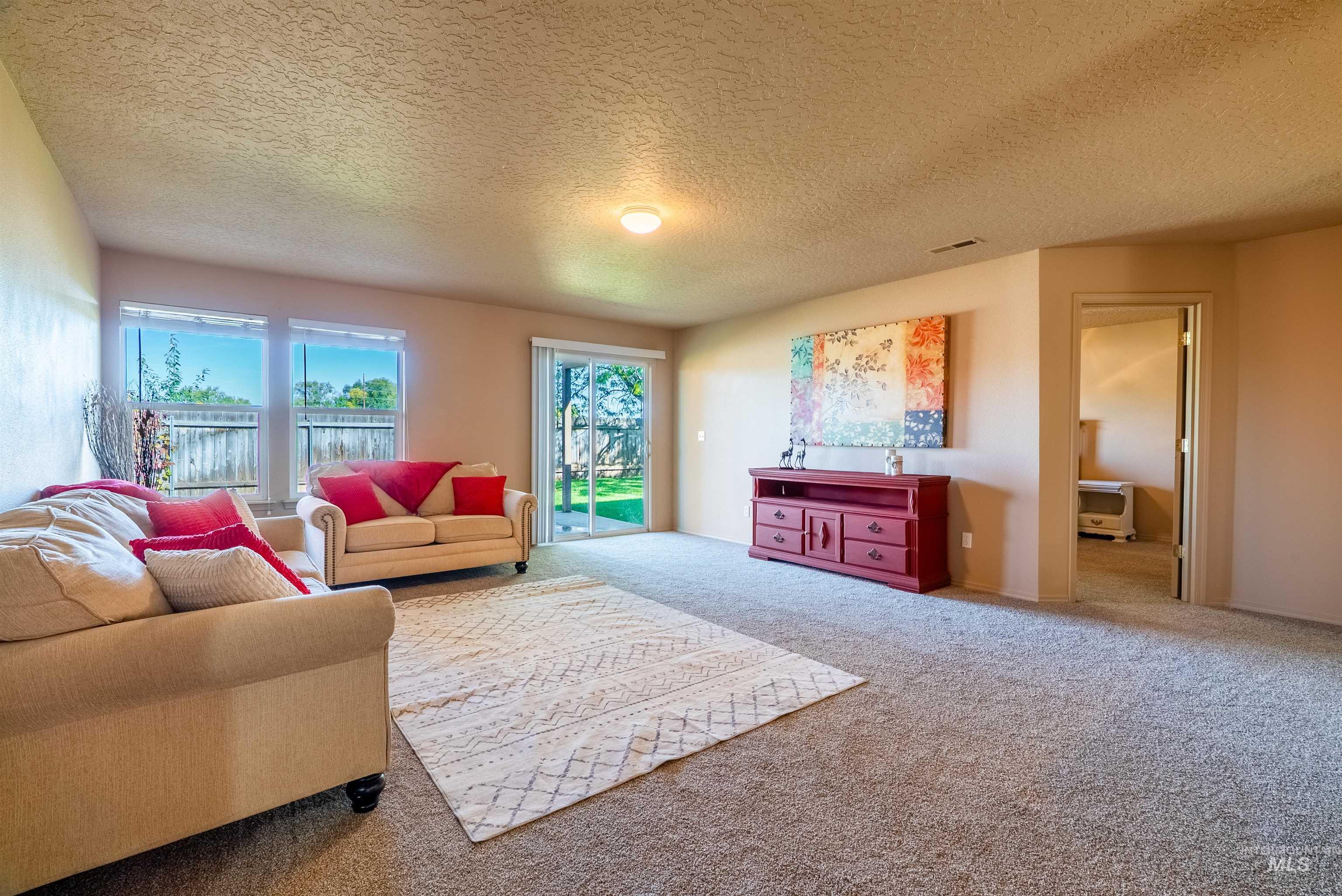 Carpeted living room featuring a textured ceiling and baseboards