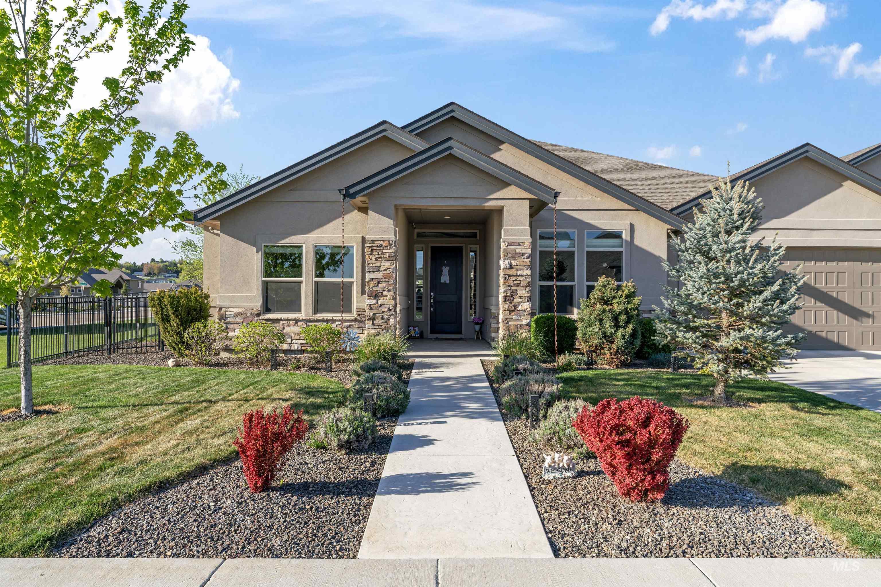 View of front of house featuring an attached garage, stone siding, and stucco siding