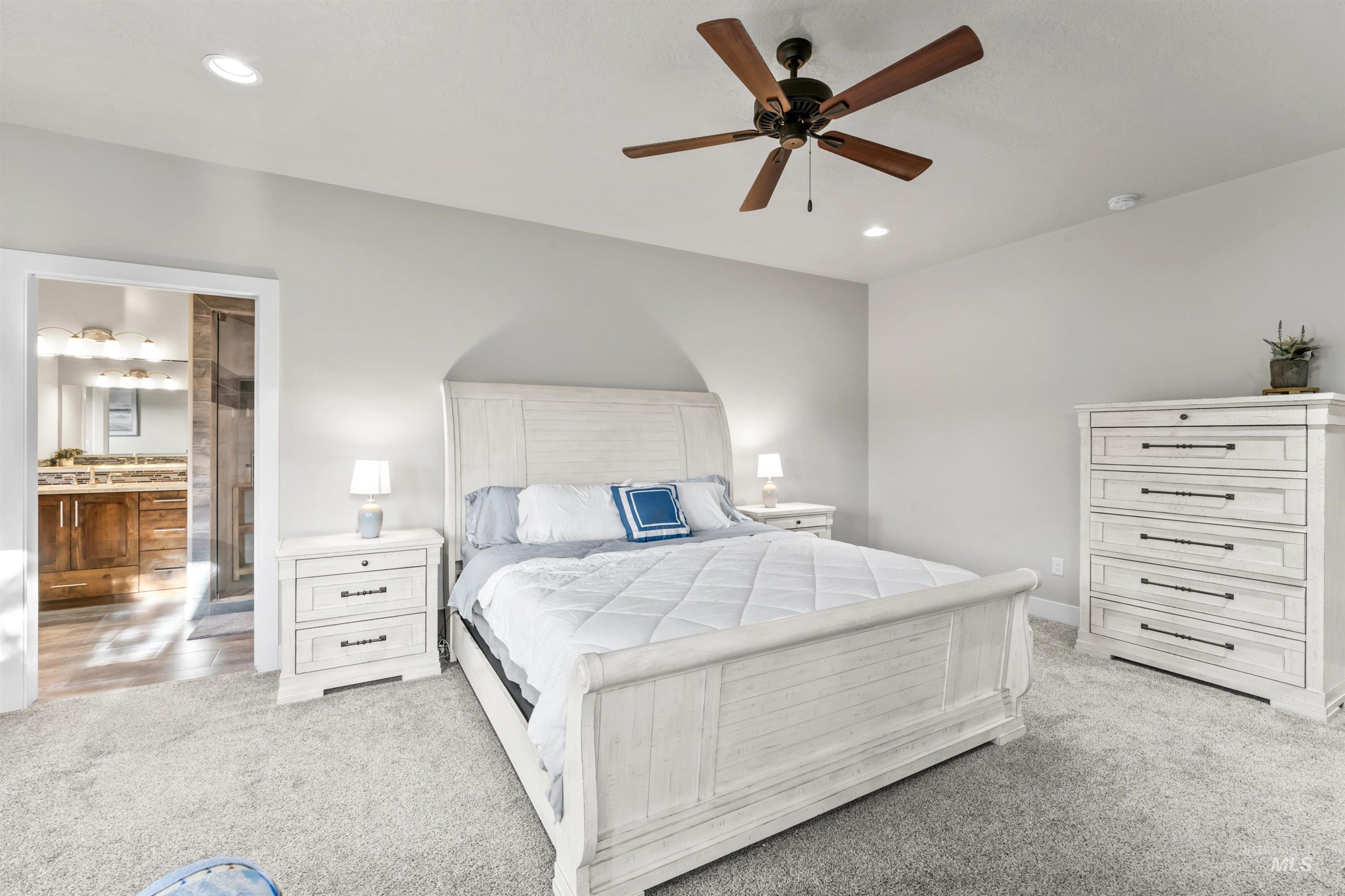 Bedroom with light colored carpet, recessed lighting, ceiling fan, and connected bathroom