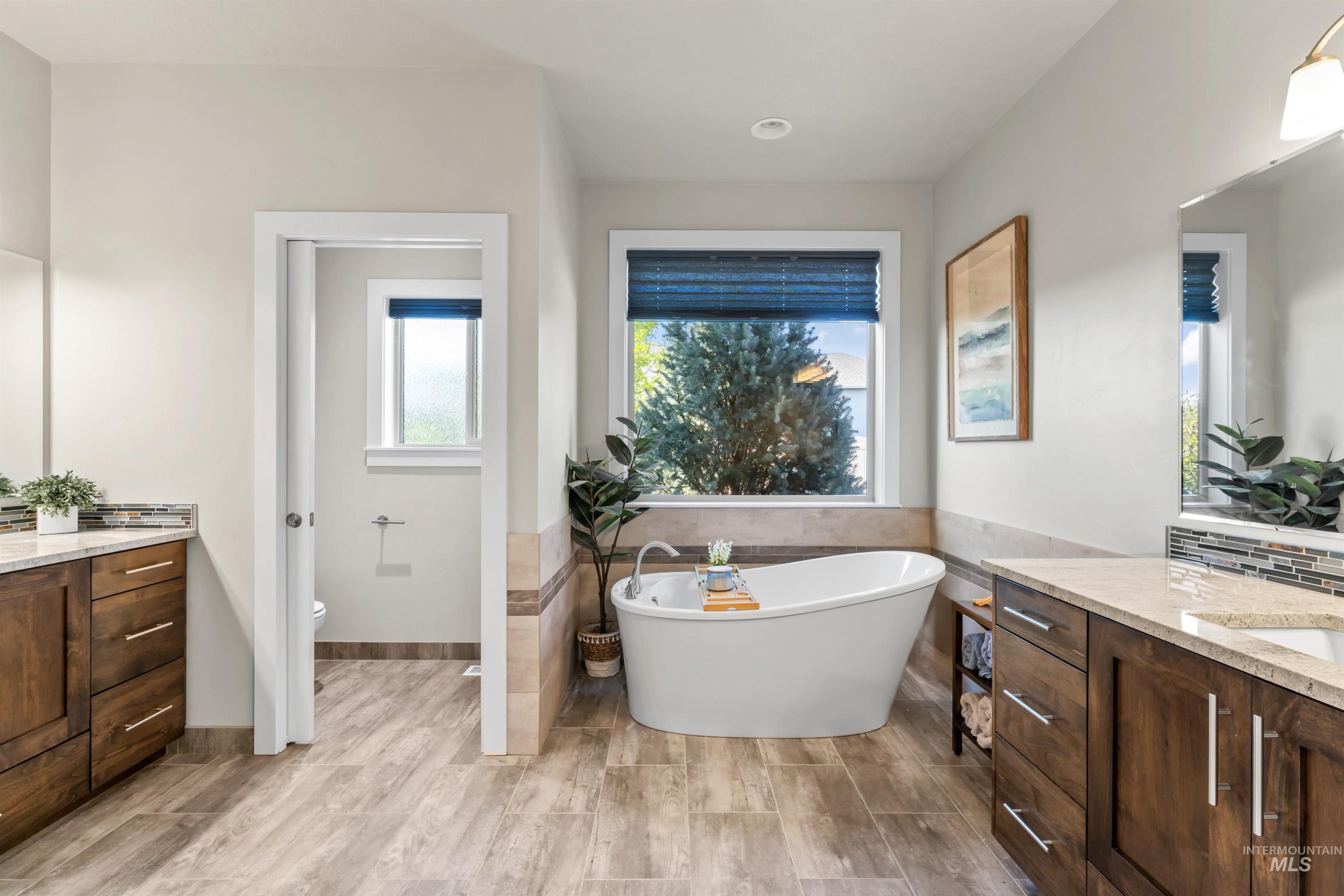 Full bathroom featuring vanity, a freestanding tub, tile walls, and light wood-type flooring