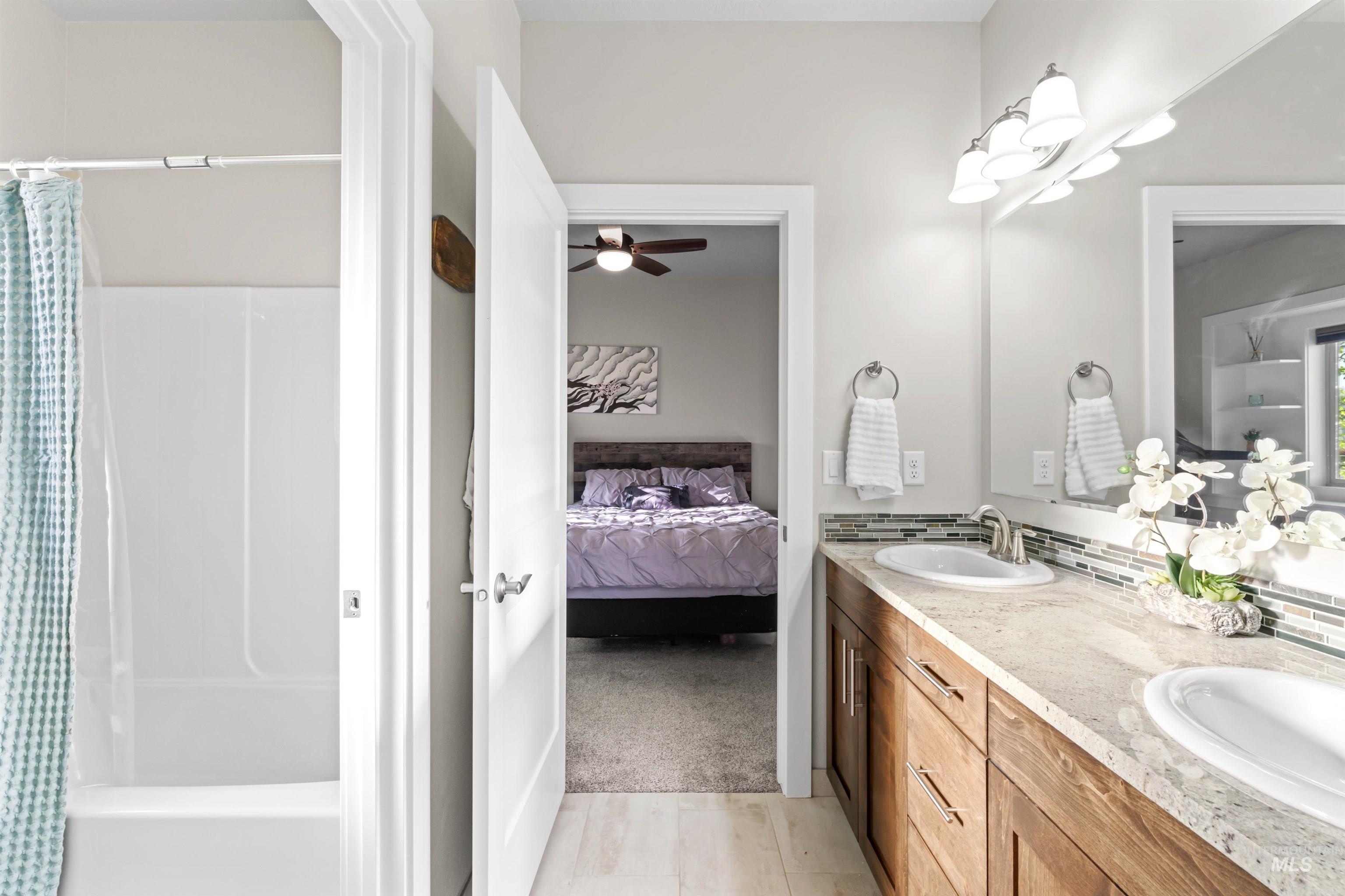 Bathroom featuring double vanity, ensuite bathroom, ceiling fan, and light colored carpet