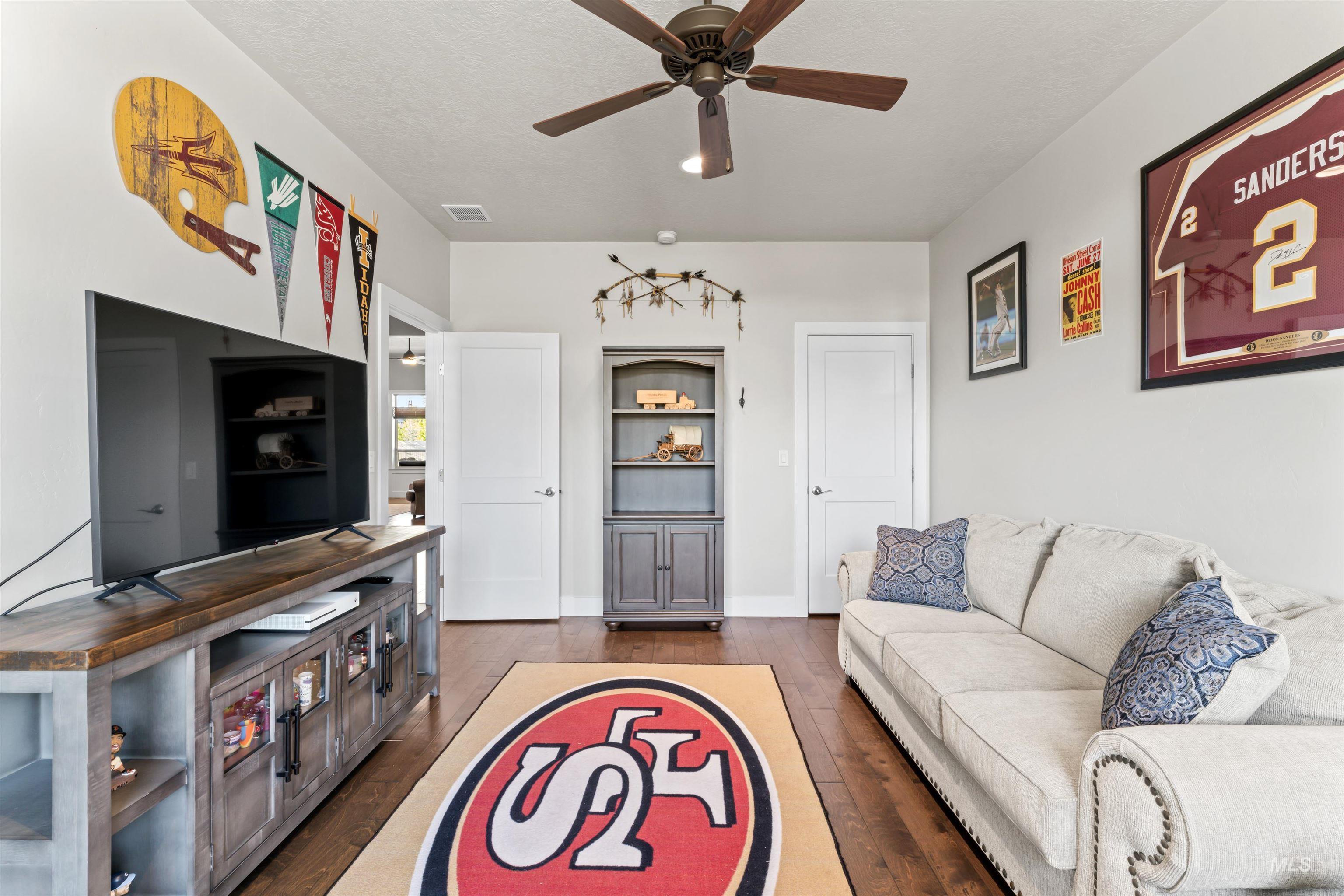 Living room featuring dark wood-style floors, ceiling fan, and a textured ceiling