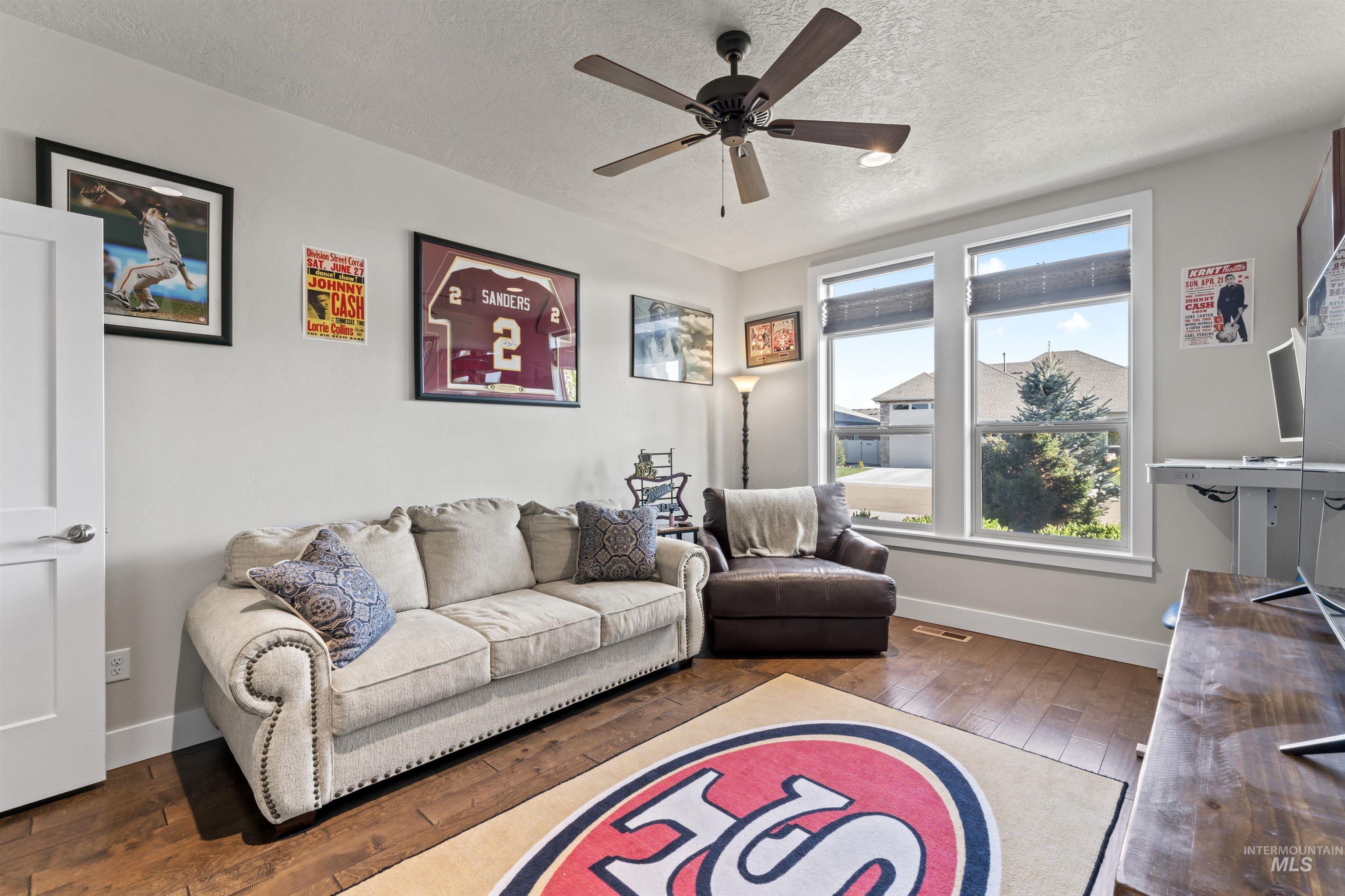 Living room featuring hardwood / wood-style flooring, a textured ceiling, and ceiling fan