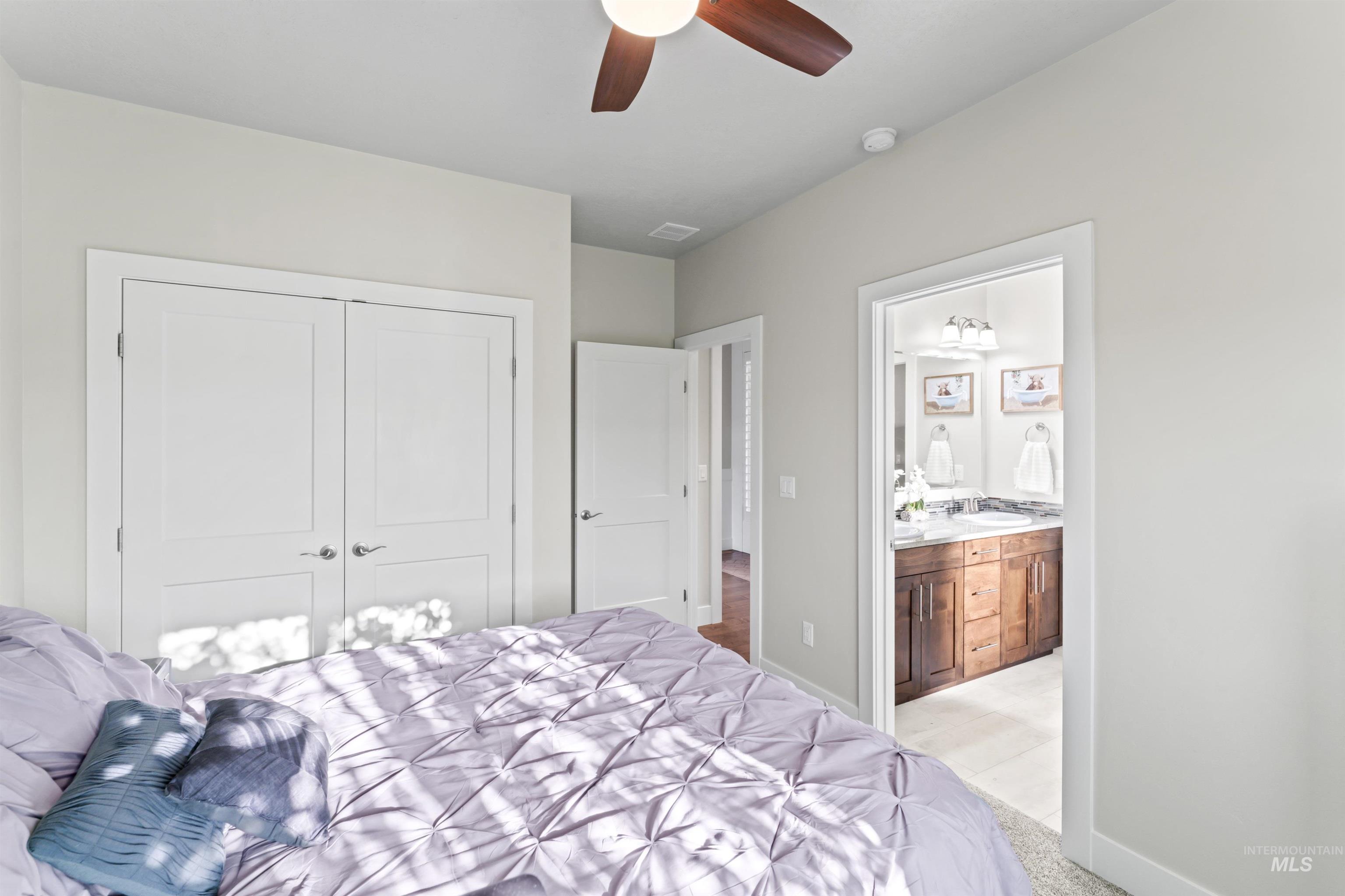 Bedroom featuring light colored carpet, a ceiling fan, a closet, and connected bathroom