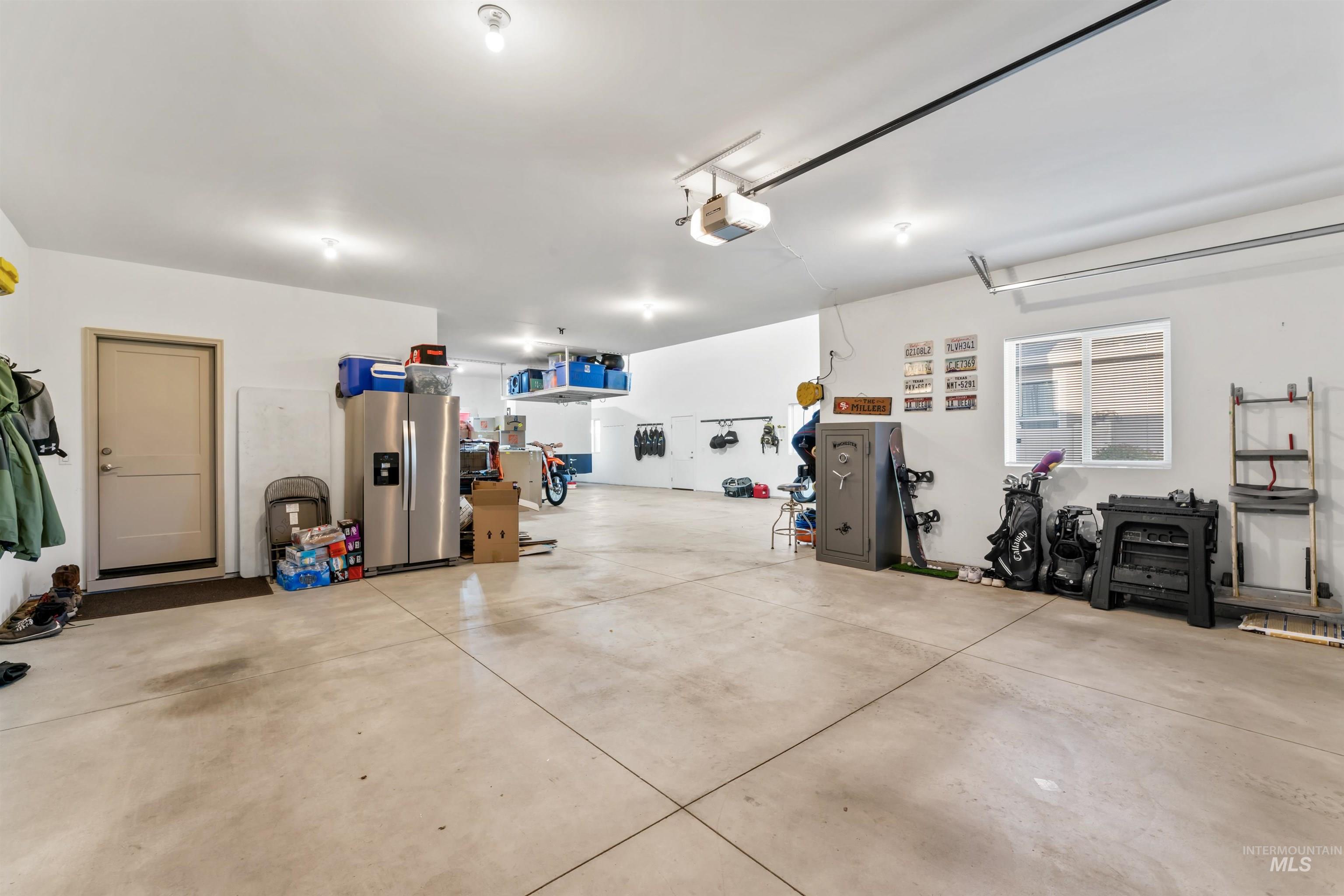 Garage with stainless steel fridge with ice dispenser and a garage door opener