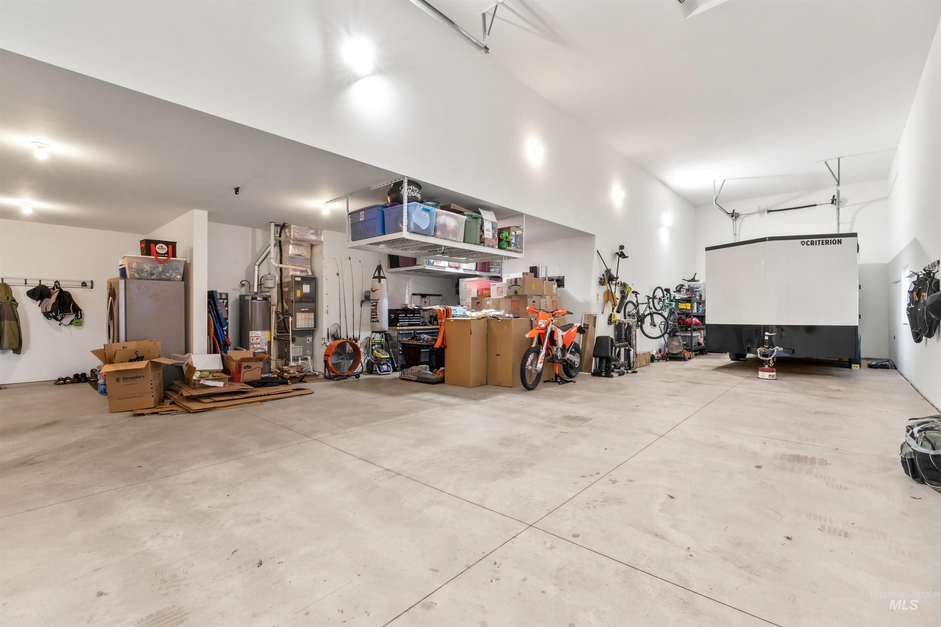 Garage featuring water heater, heating unit, and freestanding refrigerator