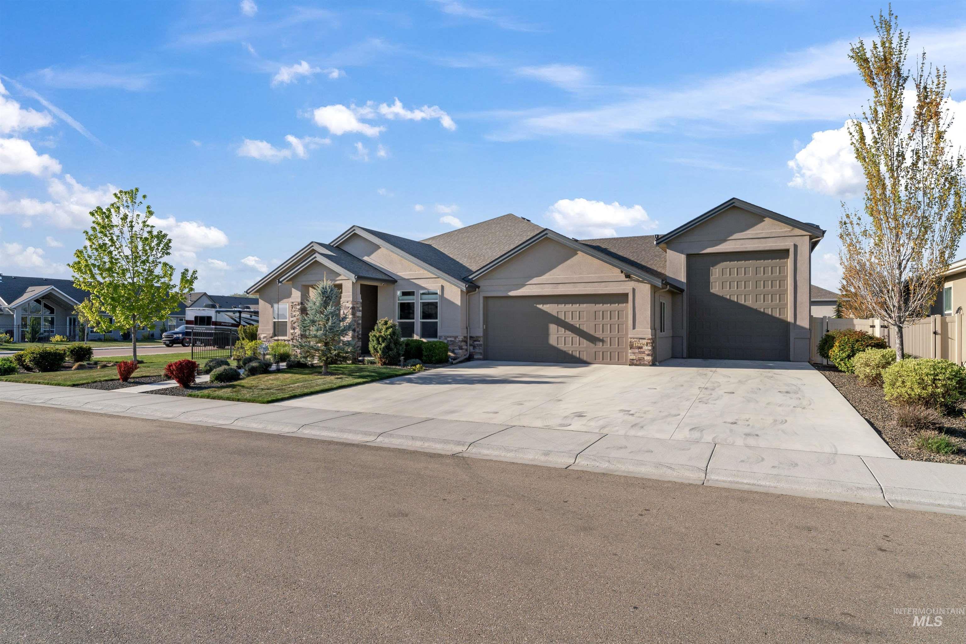 View of front facade featuring a garage, concrete driveway, and stone siding