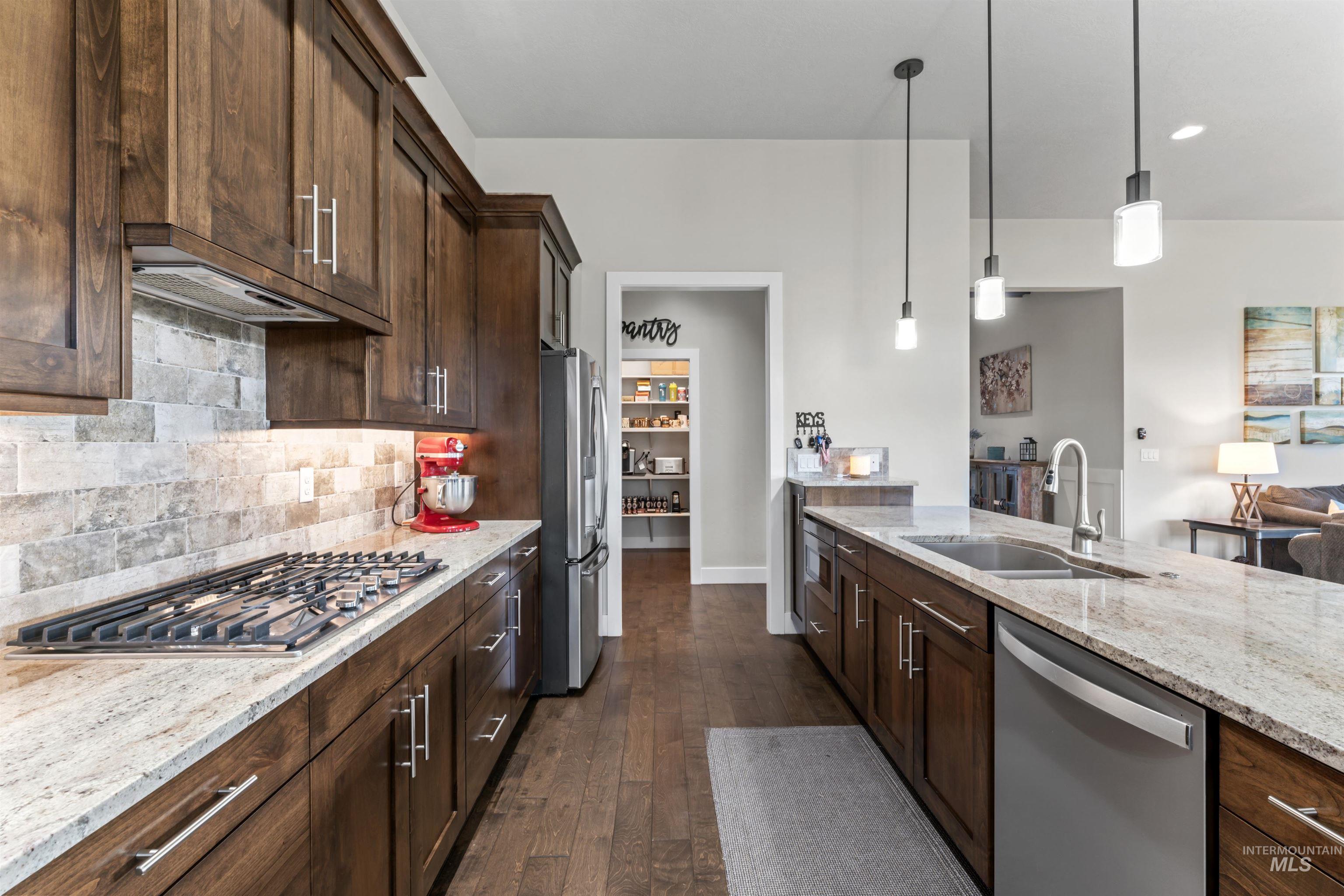 Kitchen with light stone counters, dark brown cabinetry, stainless steel appliances, backsplash, and recessed lighting