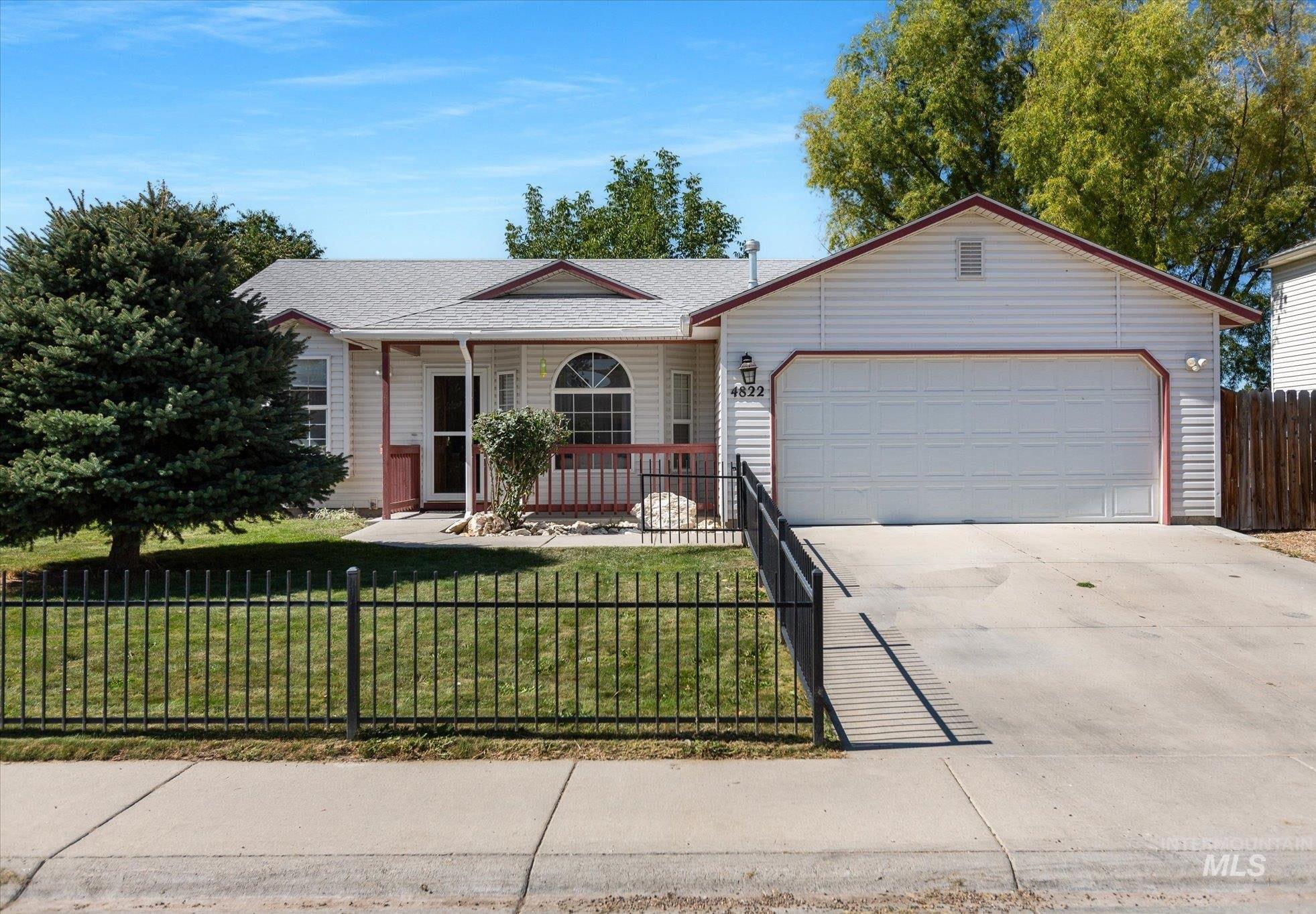 Ranch-style house with a fenced front yard, concrete driveway, a garage, a porch, and a shingled roof