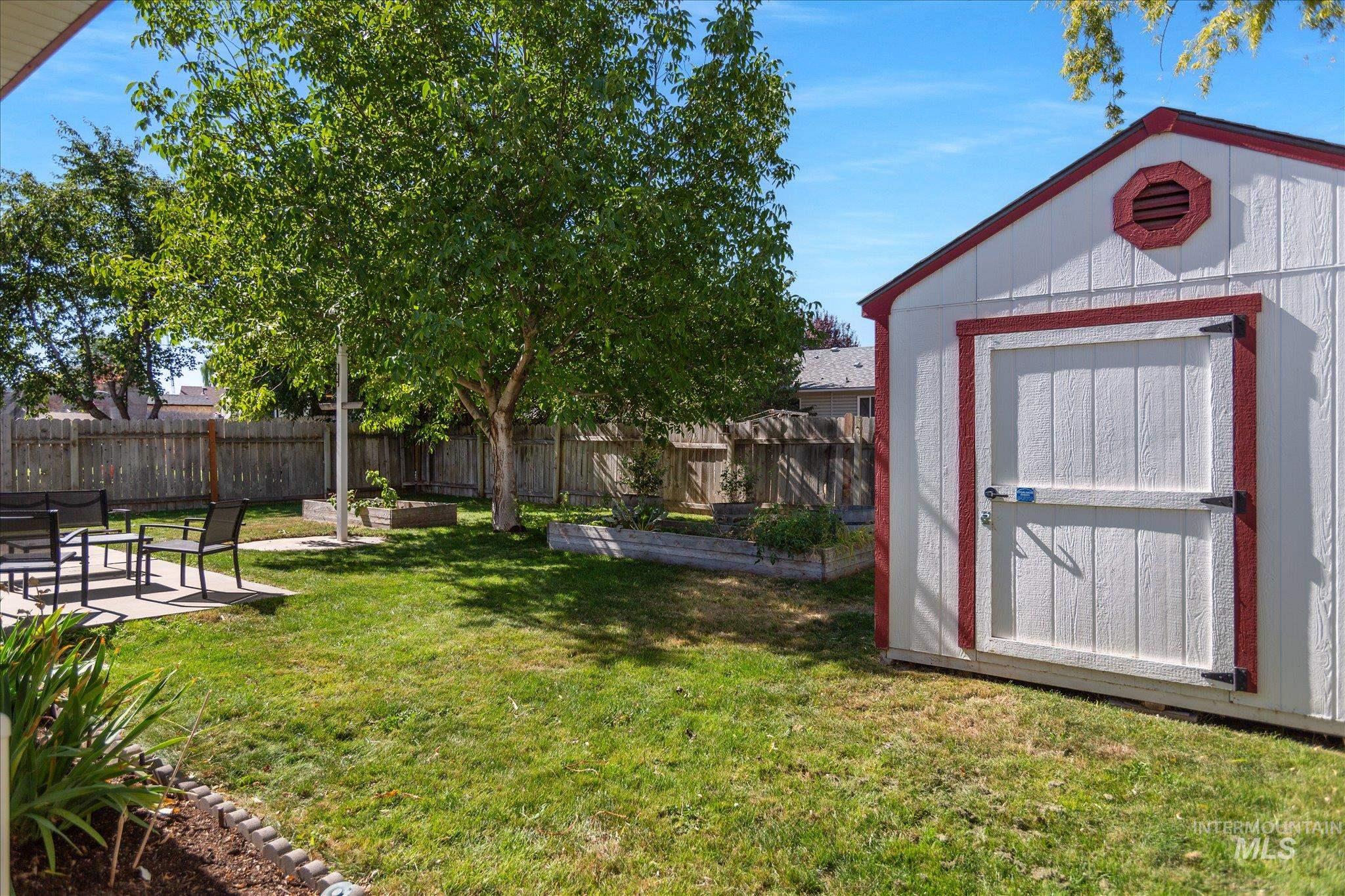 Fenced backyard featuring a patio area, a shed, and a vegetable garden