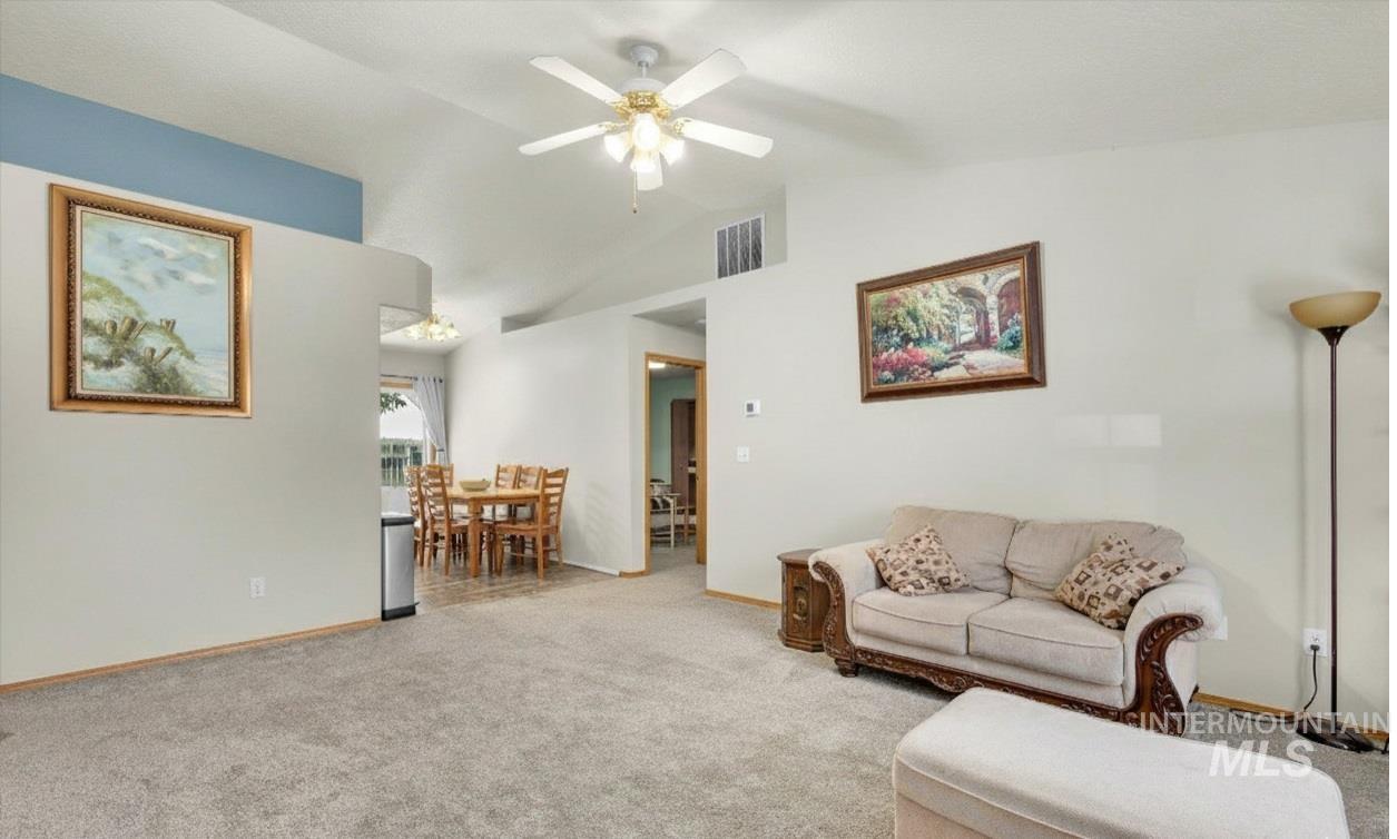 Living area with lofted ceiling, carpet flooring, and ceiling fan