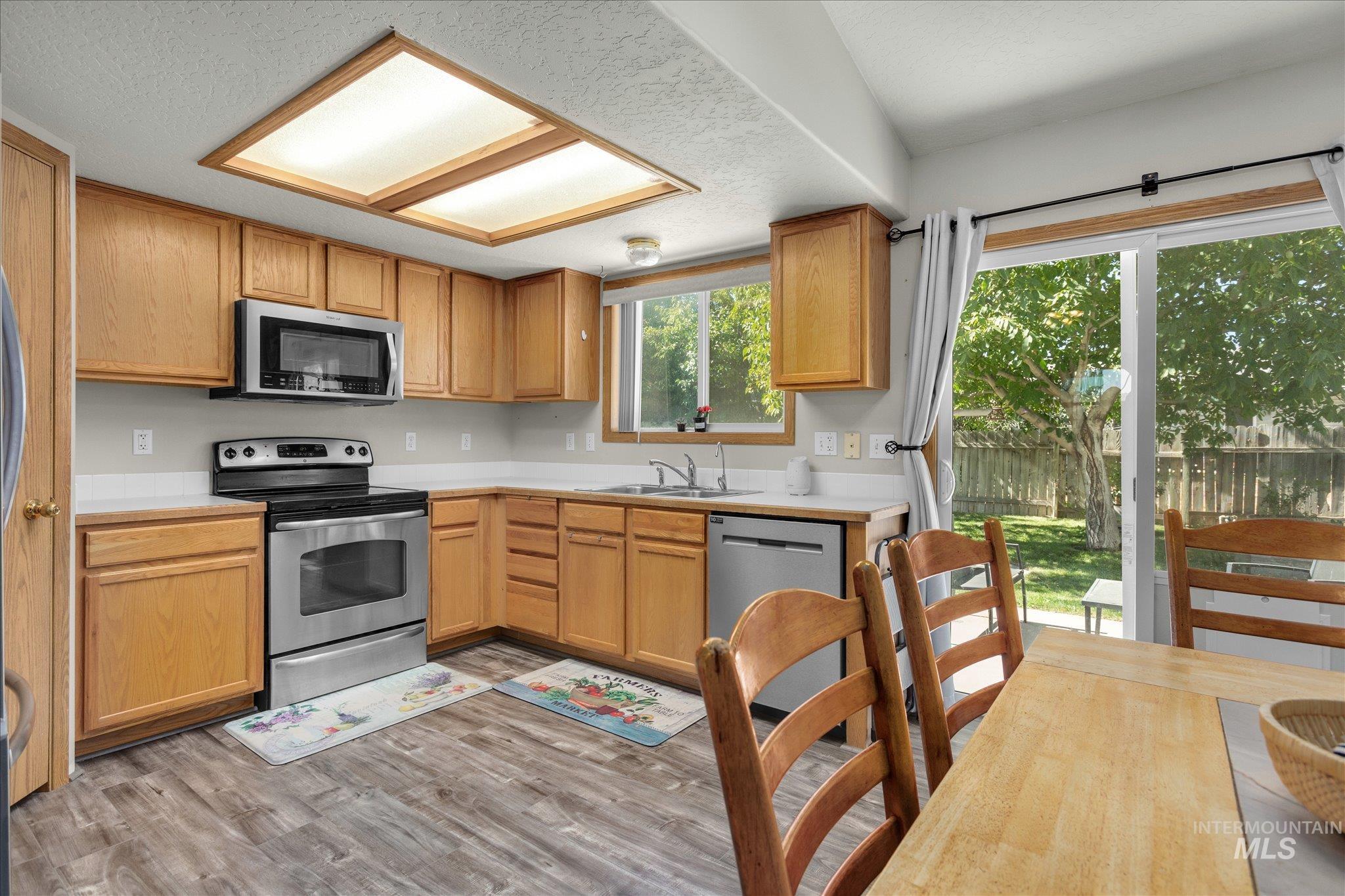 Kitchen featuring light countertops, stainless steel appliances, light wood-type flooring, and a textured ceiling