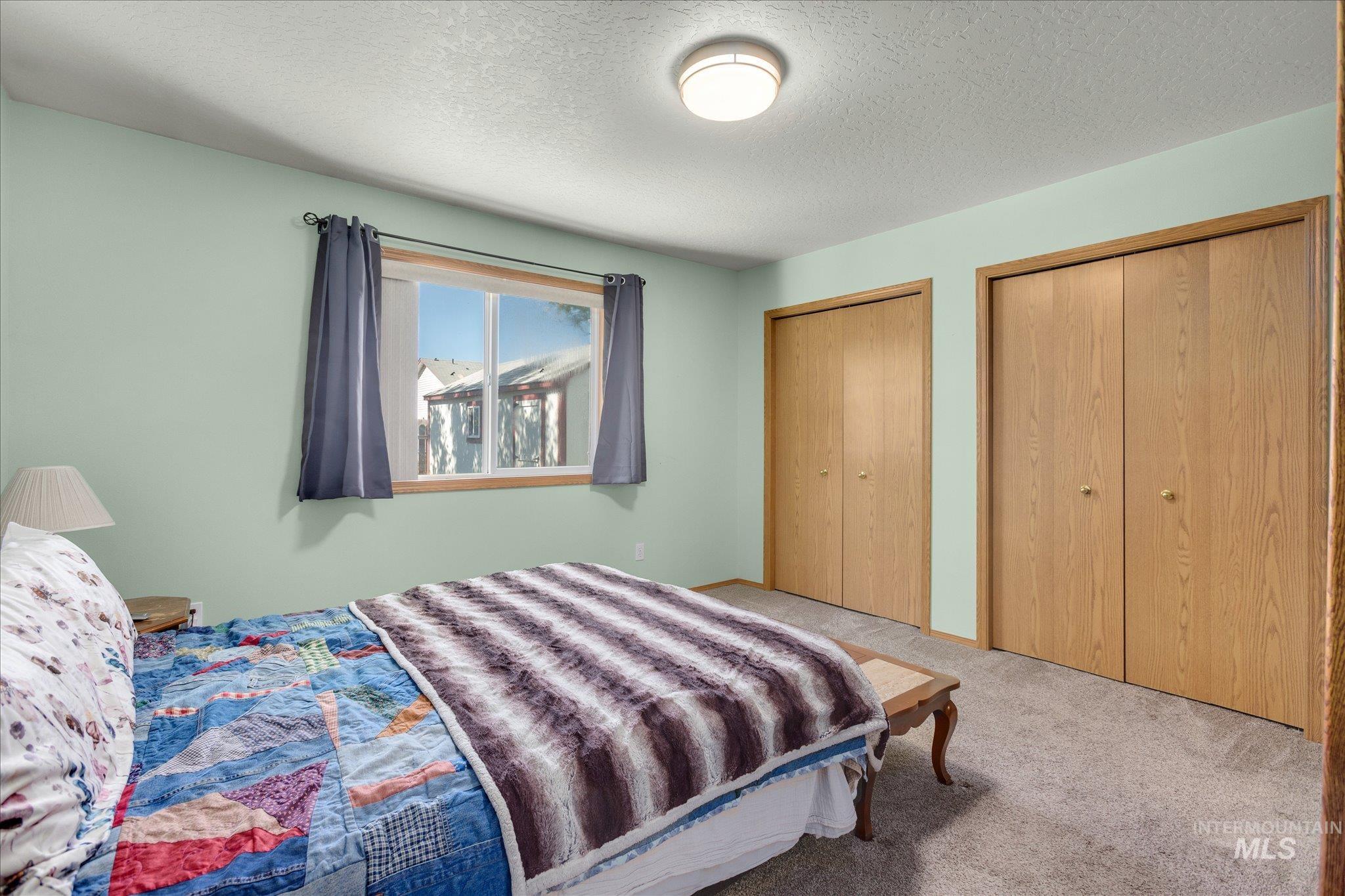 Bedroom with carpet, multiple closets, and a textured ceiling