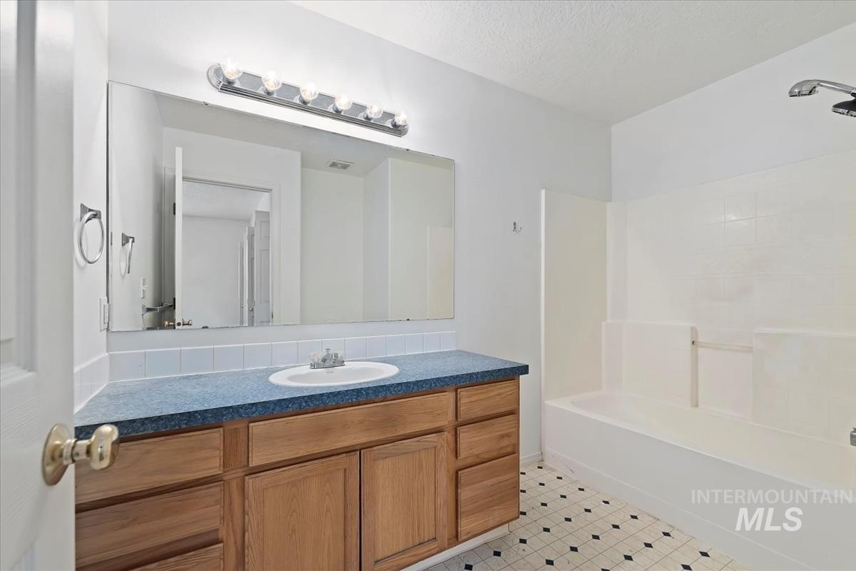 Bathroom with vanity, shower / tub combination, and a textured ceiling