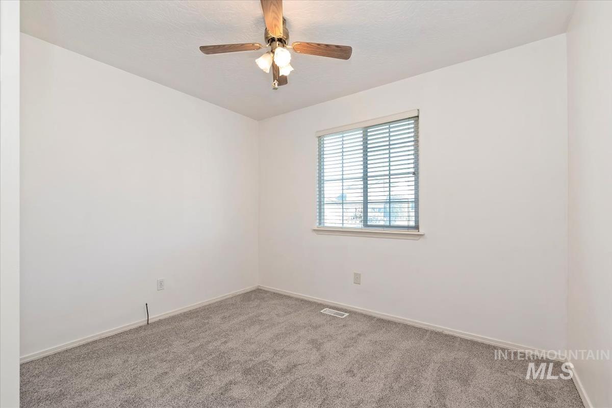 Carpeted spare room featuring baseboards and a ceiling fan
