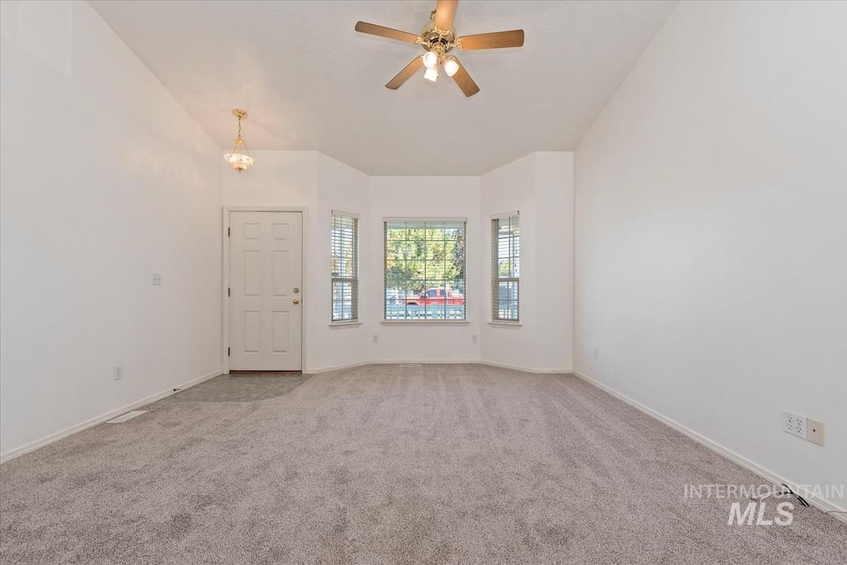 Carpeted spare room featuring ceiling fan and high vaulted ceiling