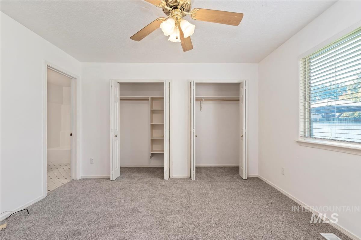 Unfurnished bedroom featuring two closets, light carpet, and ceiling fan