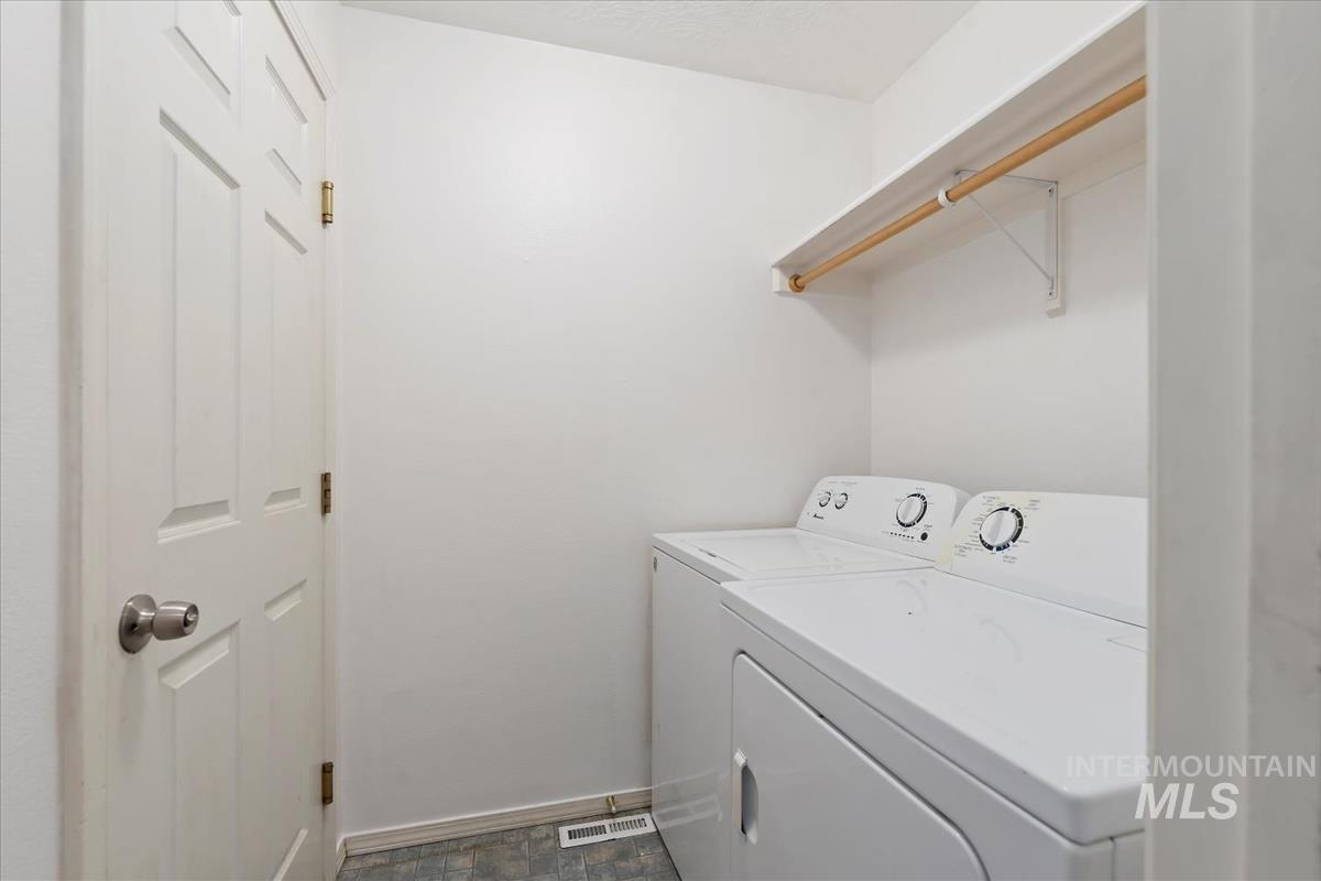 Laundry room featuring separate washer and dryer and stone finish floors