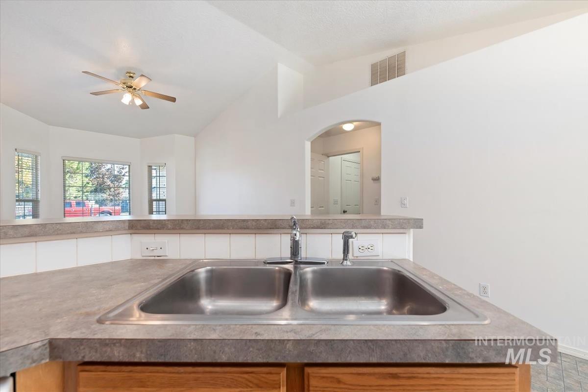 Kitchen with lofted ceiling, a ceiling fan, and light countertops