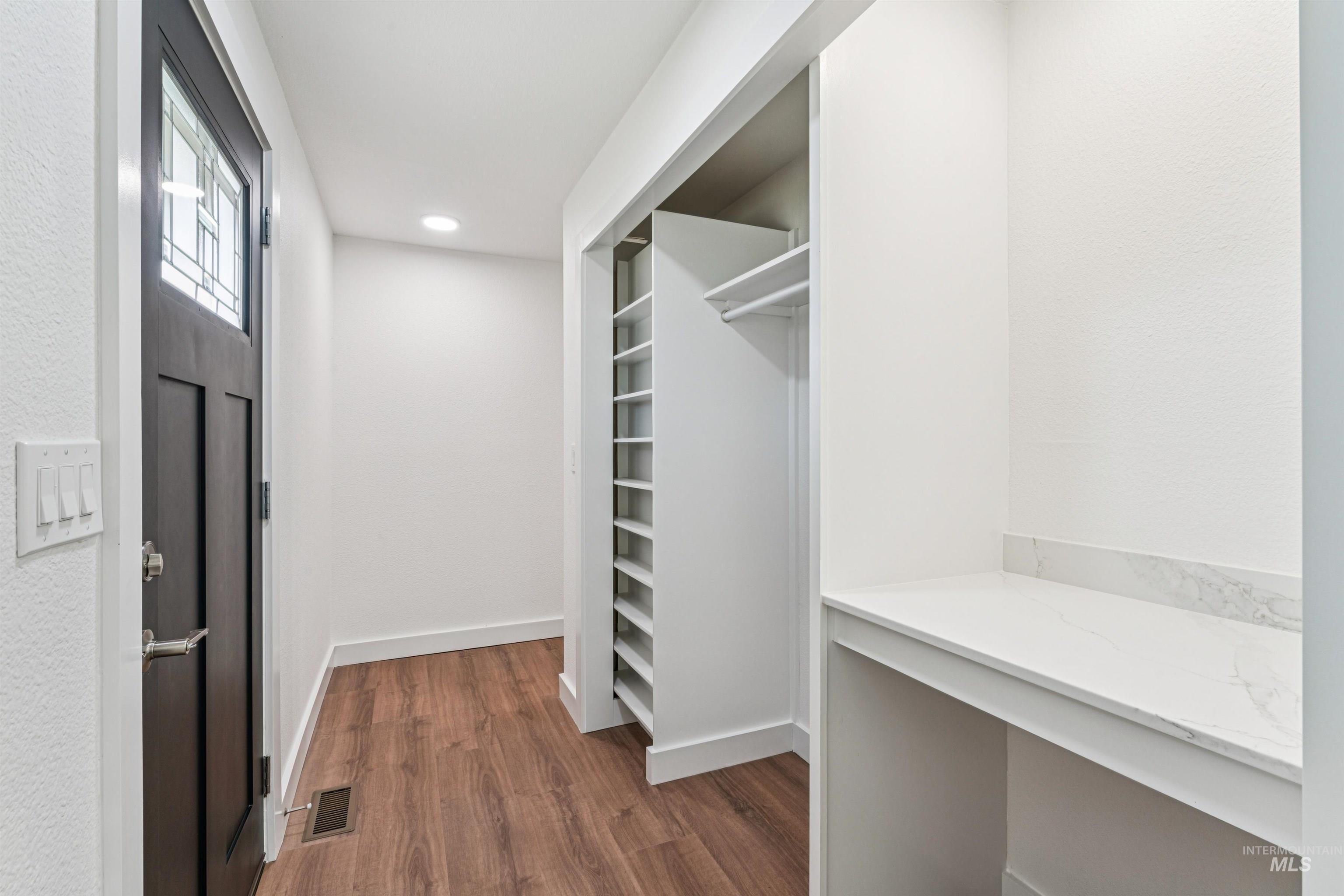 Spacious closet featuring dark wood-type flooring and built in desk