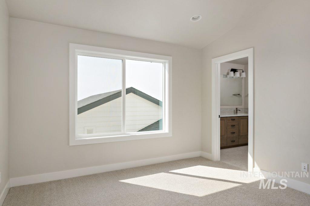 Unfurnished bedroom with light carpet and ensuite bath