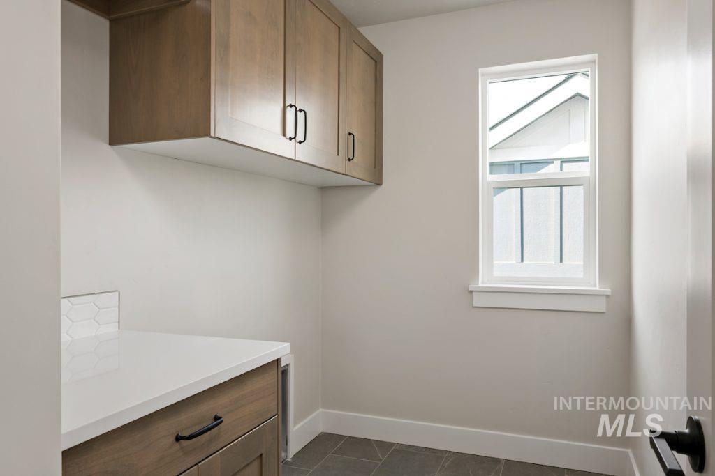 Washroom with baseboards and dark tile patterned floors