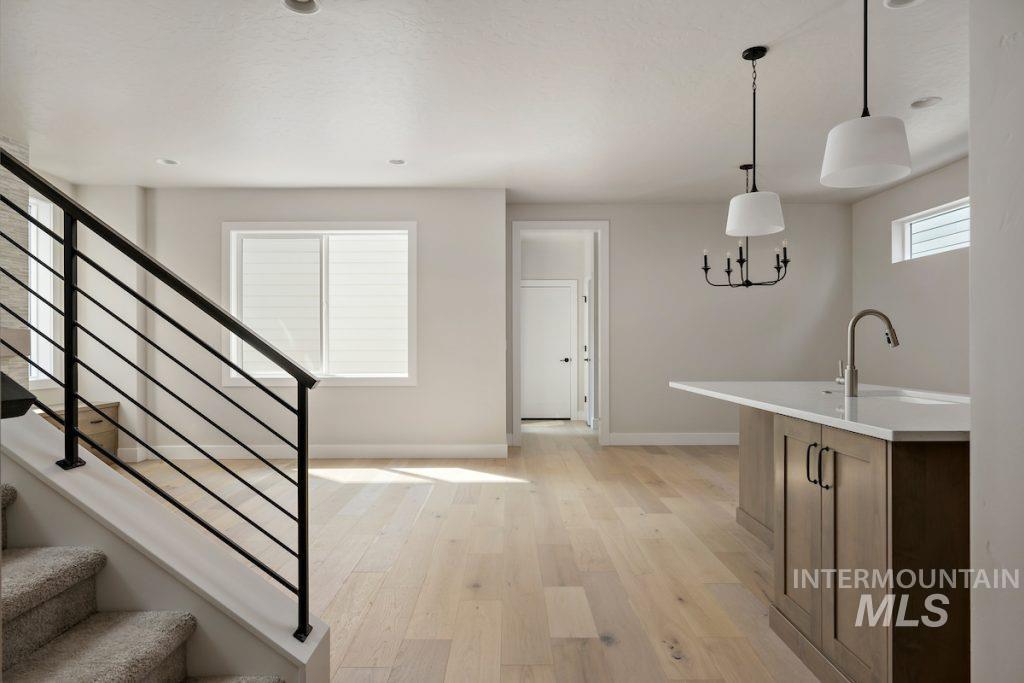 Kitchen featuring light wood-style floors, hanging light fixtures, and light stone countertops