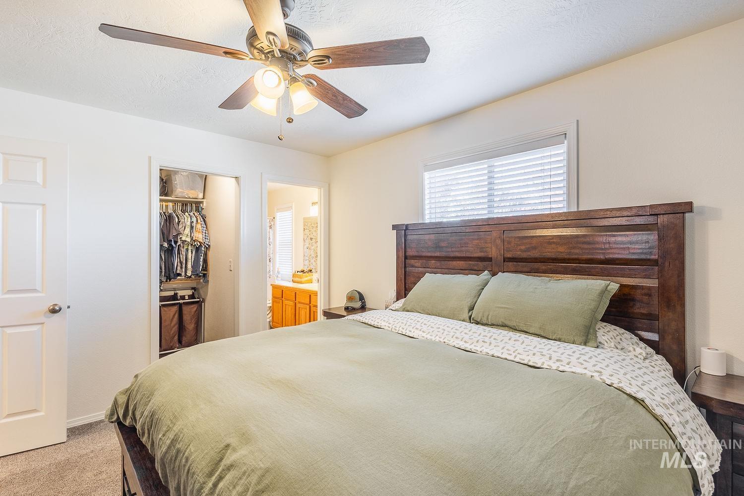 Bedroom with light colored carpet, ceiling fan, and a textured ceiling